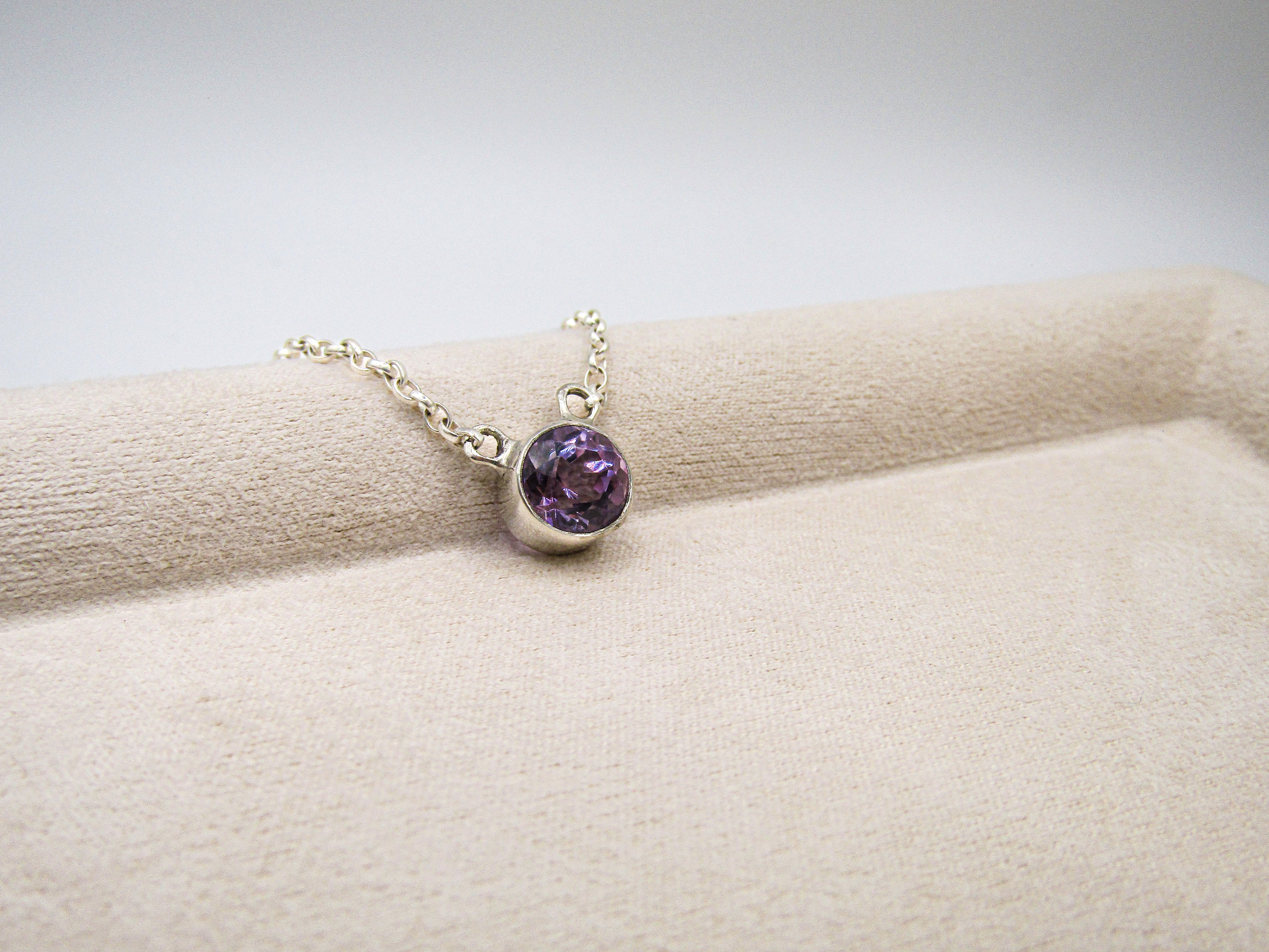 Necklace with a purple gemstone on a beige surface
