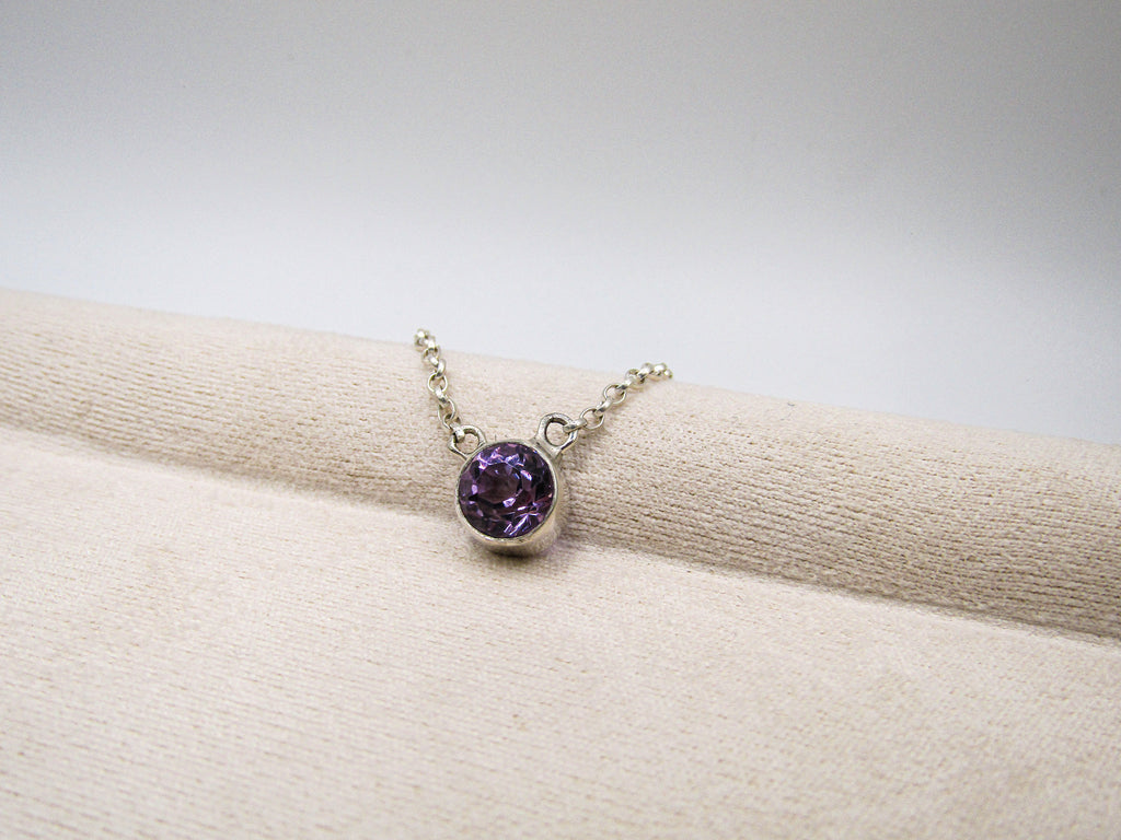 Silver bracelet with a purple gemstone on a beige fabric background