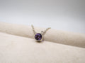 Silver bracelet with a purple gemstone on a beige fabric background