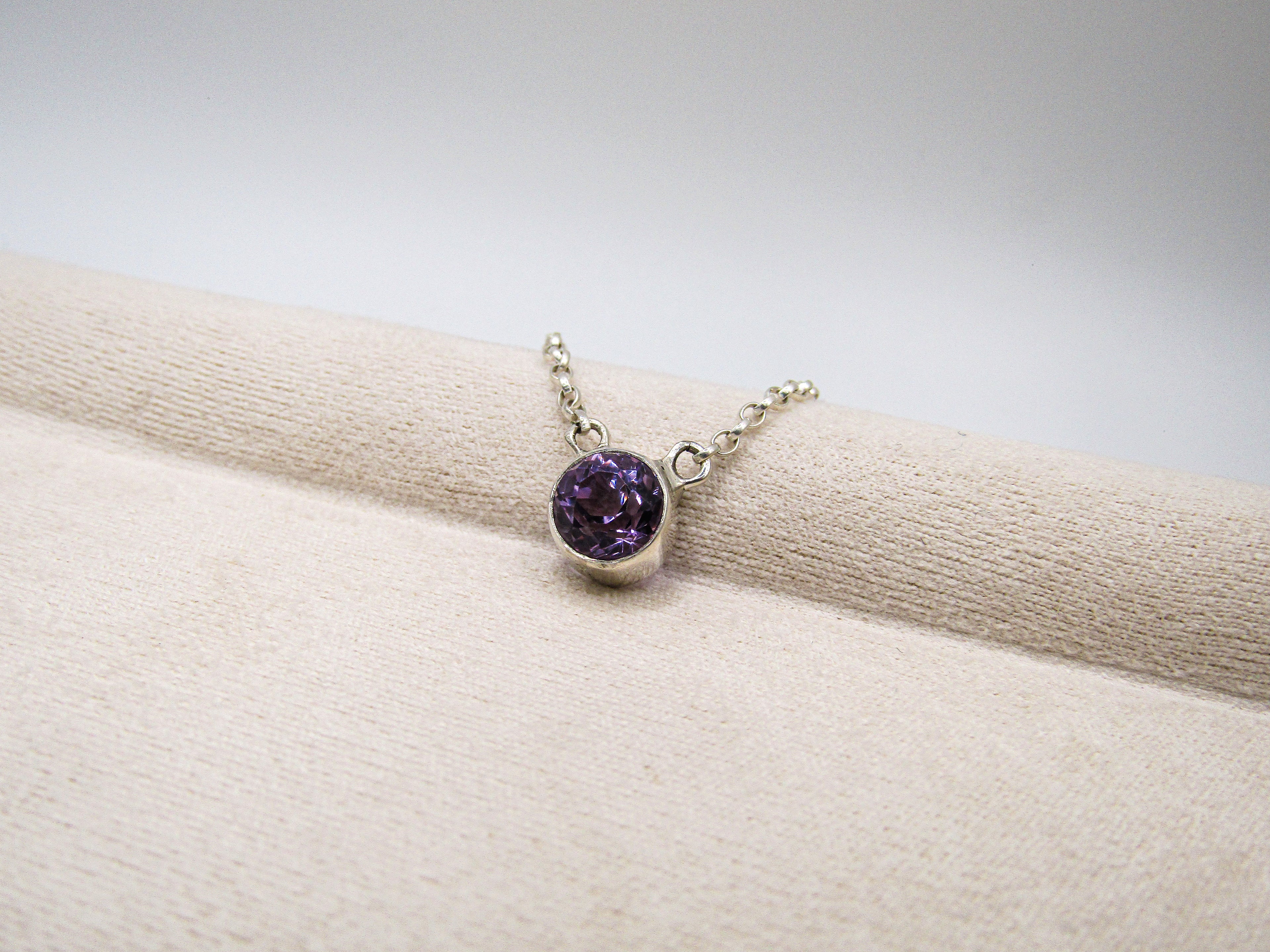 Silver bracelet with a purple gemstone on a beige surface