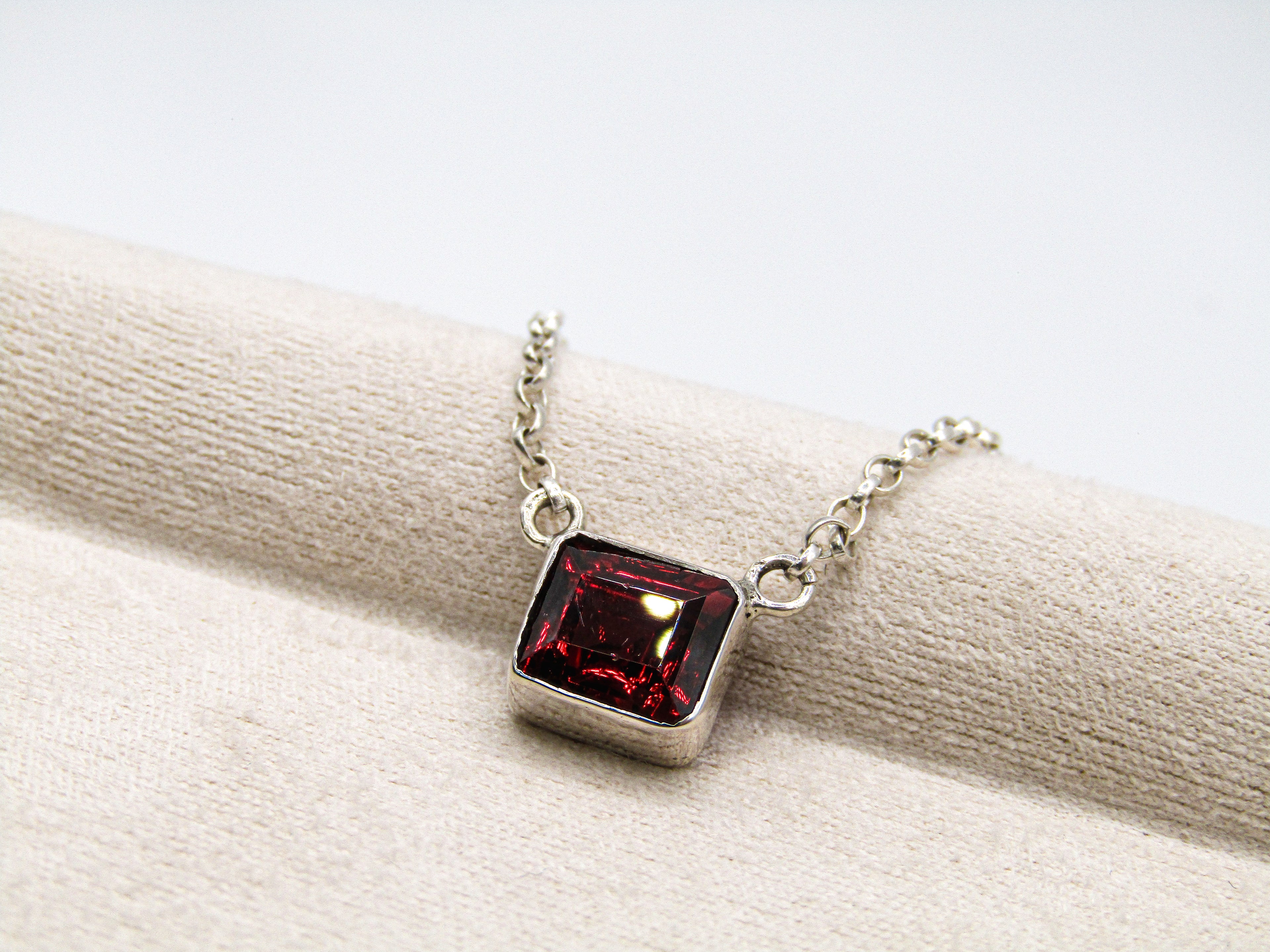 Necklace with a red gemstone pendant on a white surface