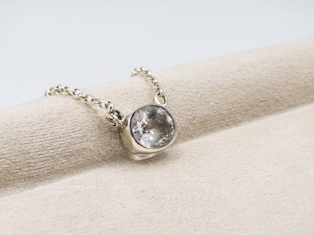 Silver necklace with a round pendant on a beige surface