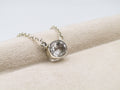 Silver necklace with a round pendant on a beige surface