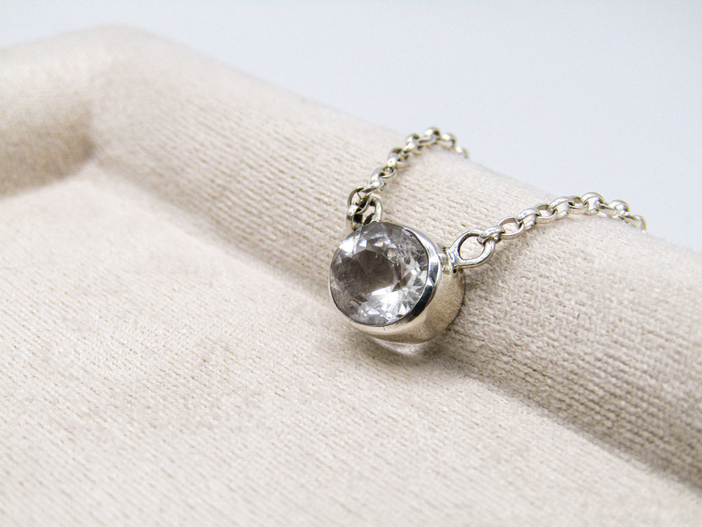 Silver bracelet with a clear gemstone on a beige fabric background