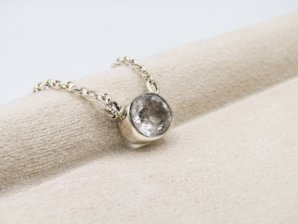 Silver bracelet with a clear gemstone on a beige surface