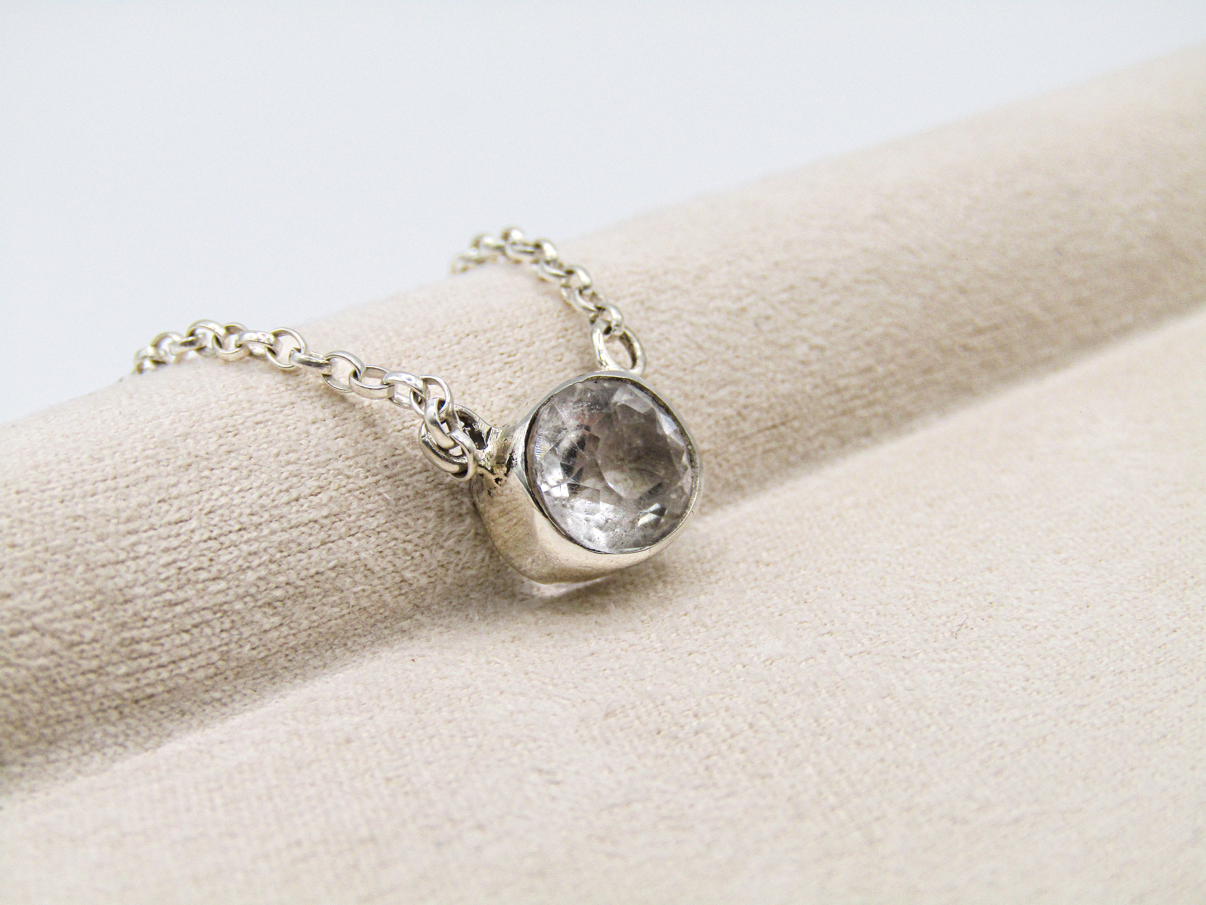 Silver bracelet with a clear gemstone on a beige surface
