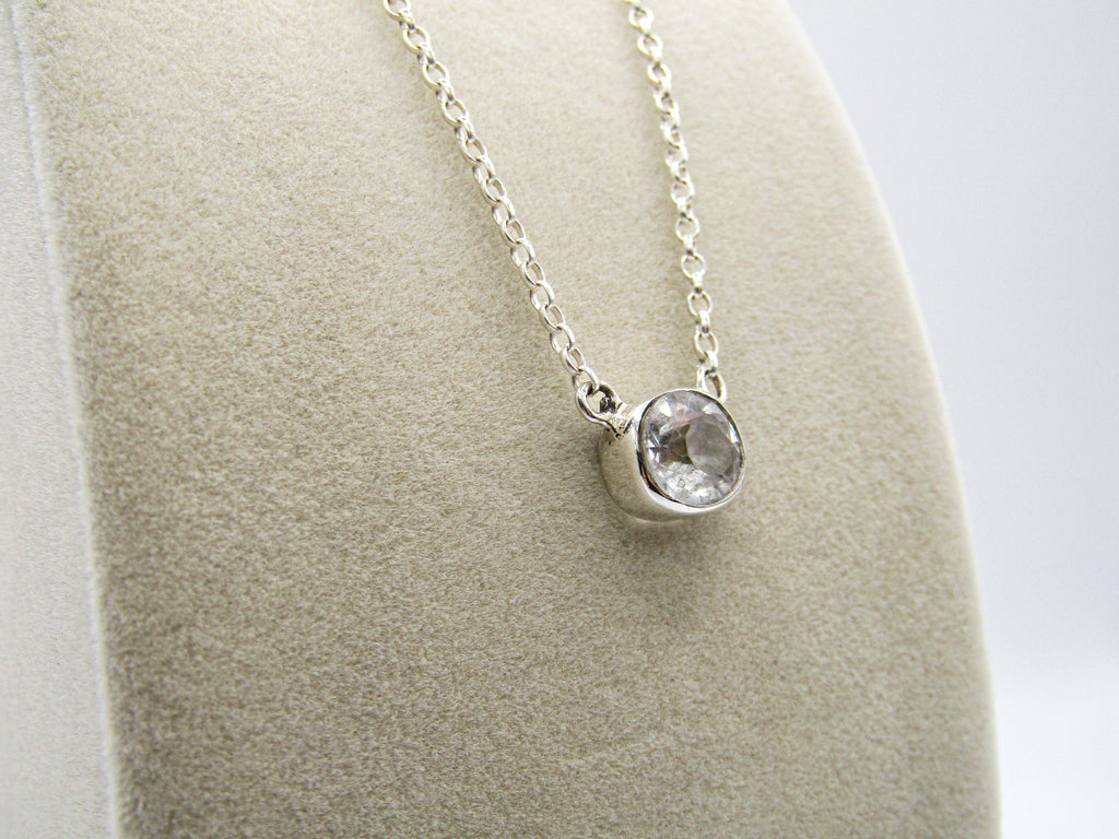 Silver necklace with a pendant on a gray stand