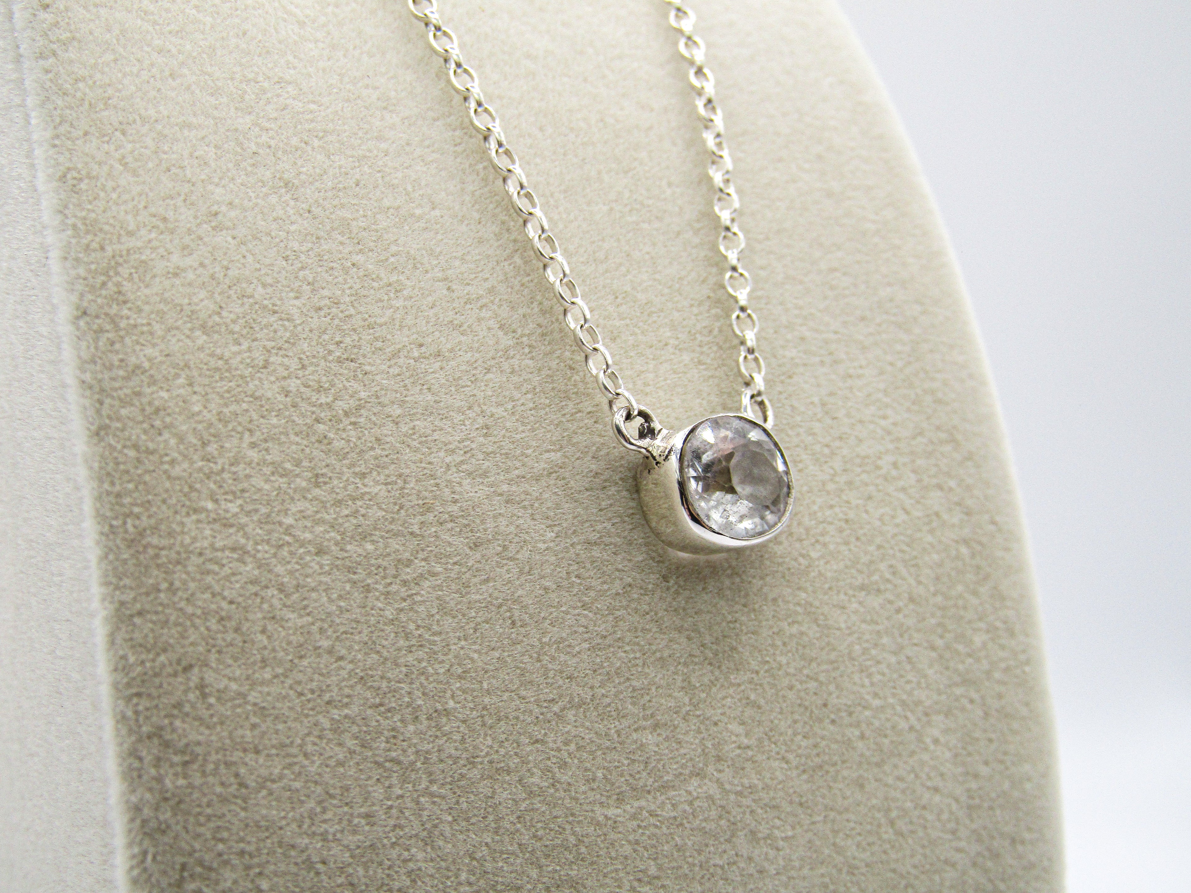 Silver necklace with a pendant on a gray stand