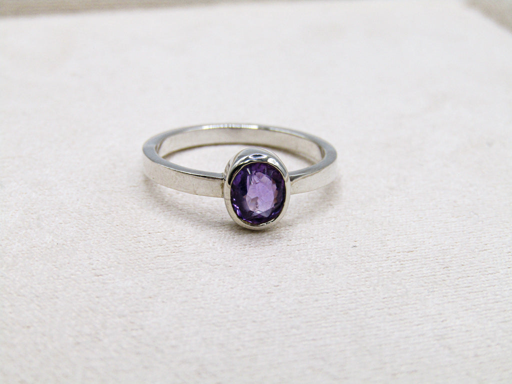 Silver ring with a purple gemstone on a white background