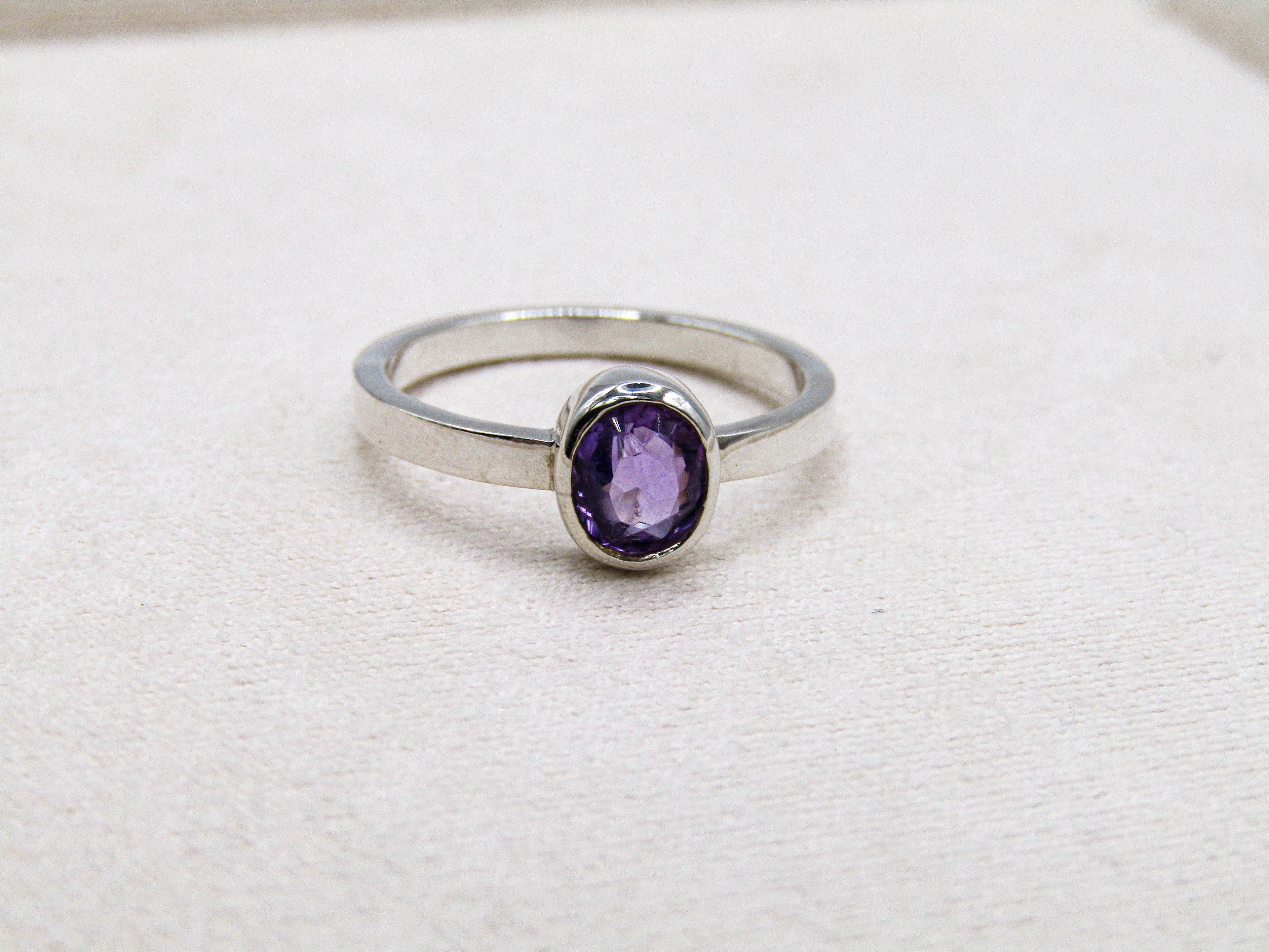 Silver ring with a purple gemstone on a white background