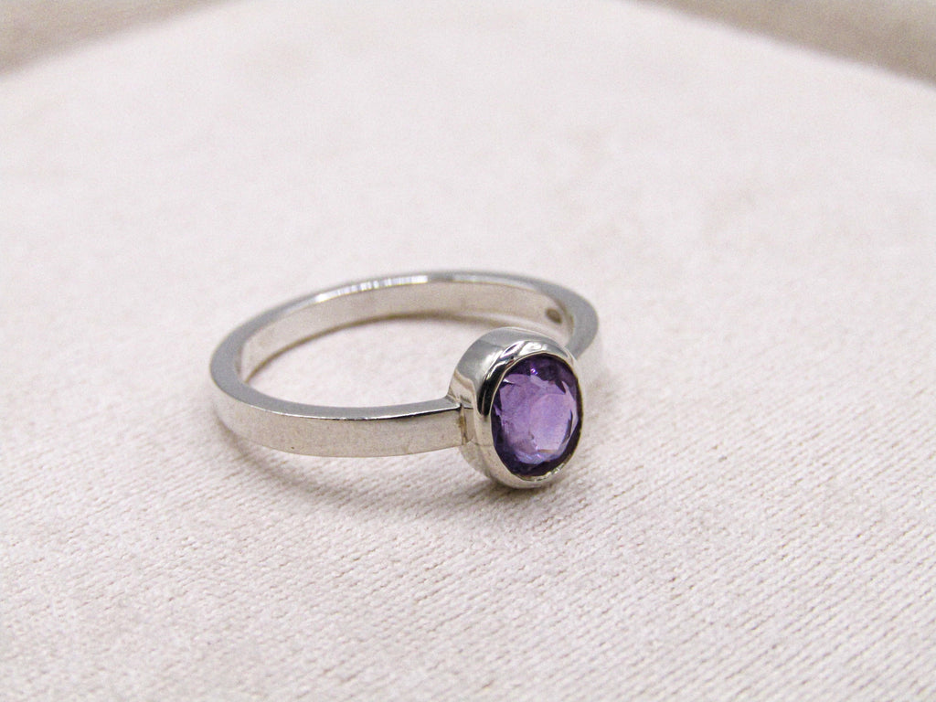 Silver ring with a purple gemstone on a white background