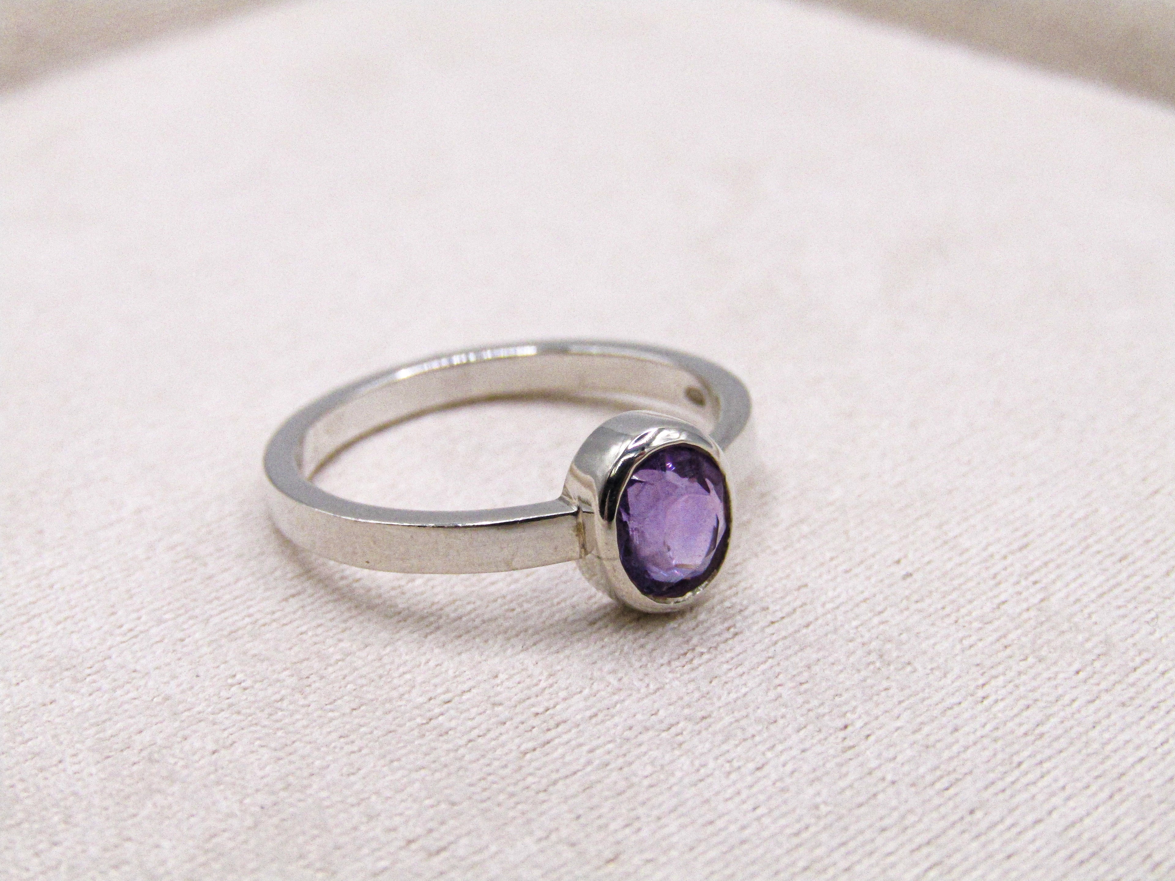 Silver ring with a purple gemstone on a white background