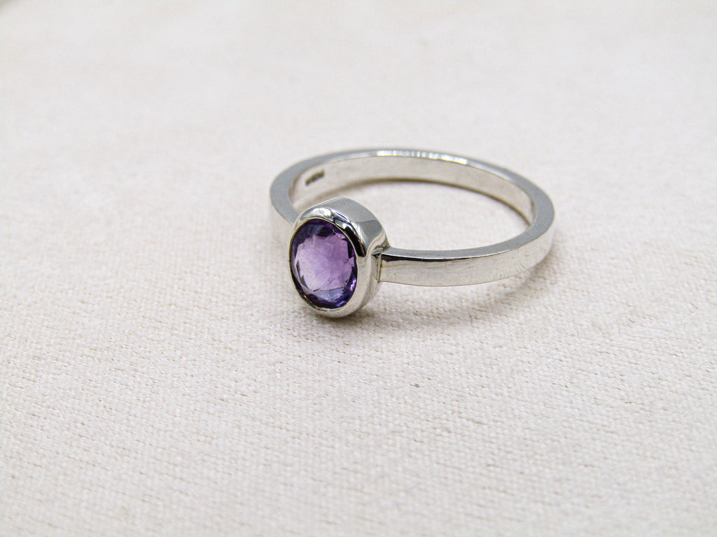 Silver ring with a purple gemstone on a white background