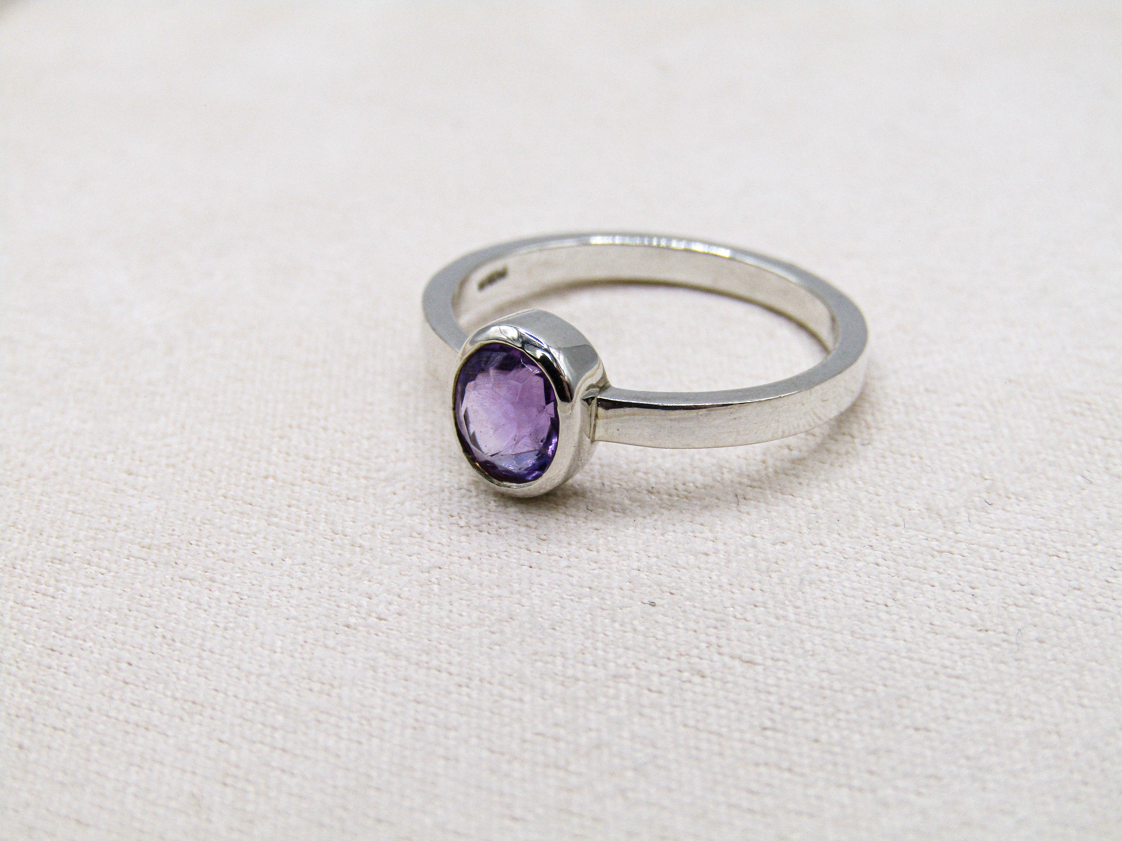 Silver ring with a purple gemstone on a white background