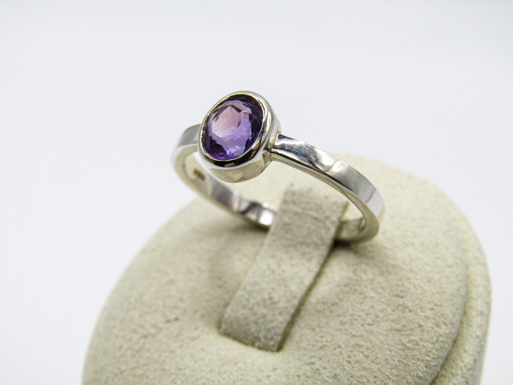 Silver ring with a purple gemstone on a white background