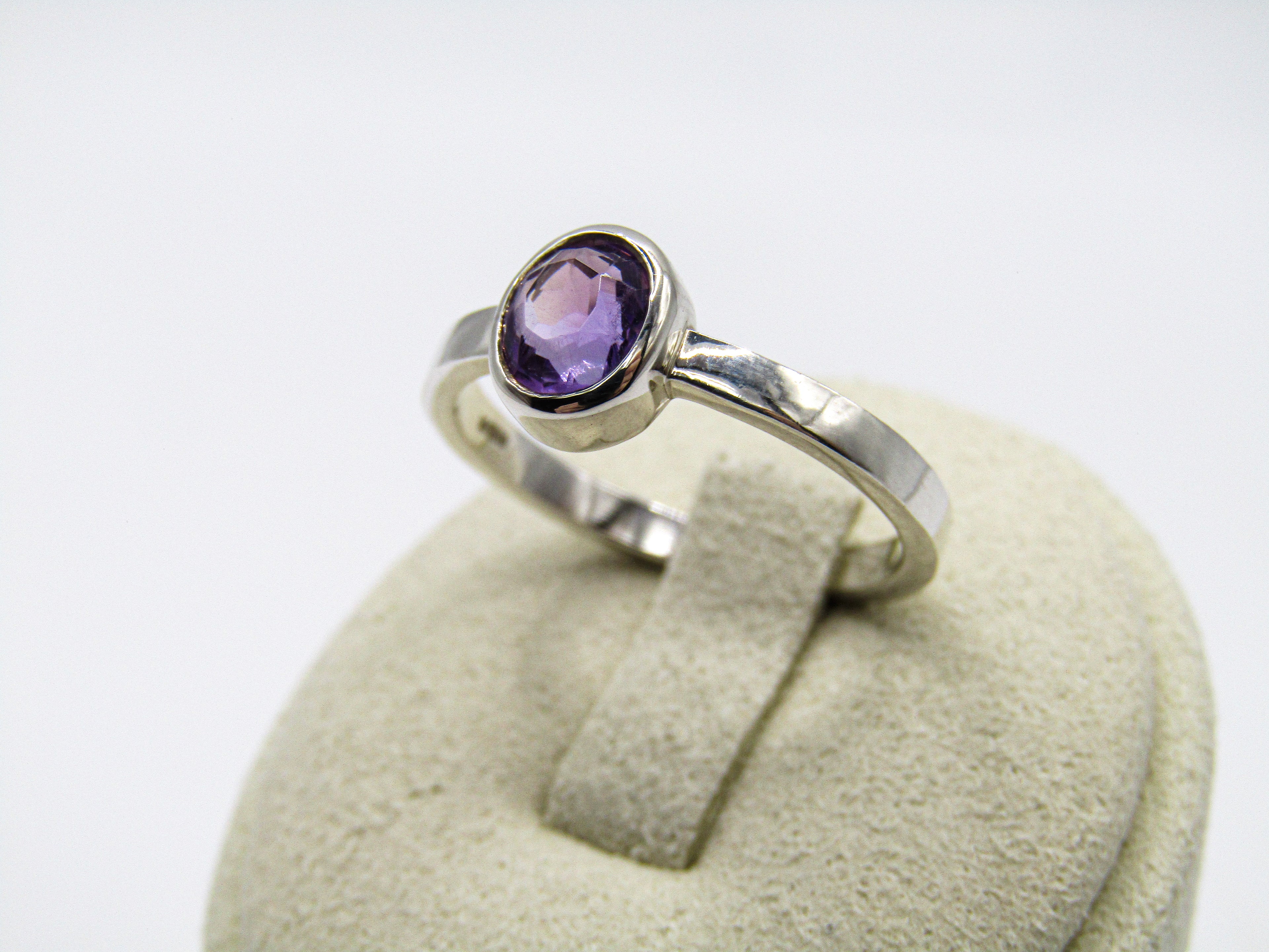 Silver ring with a purple gemstone on a white background
