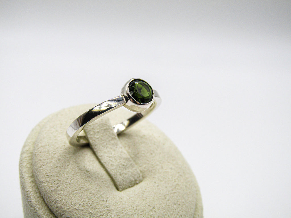Silver ring with a green gemstone on a white background