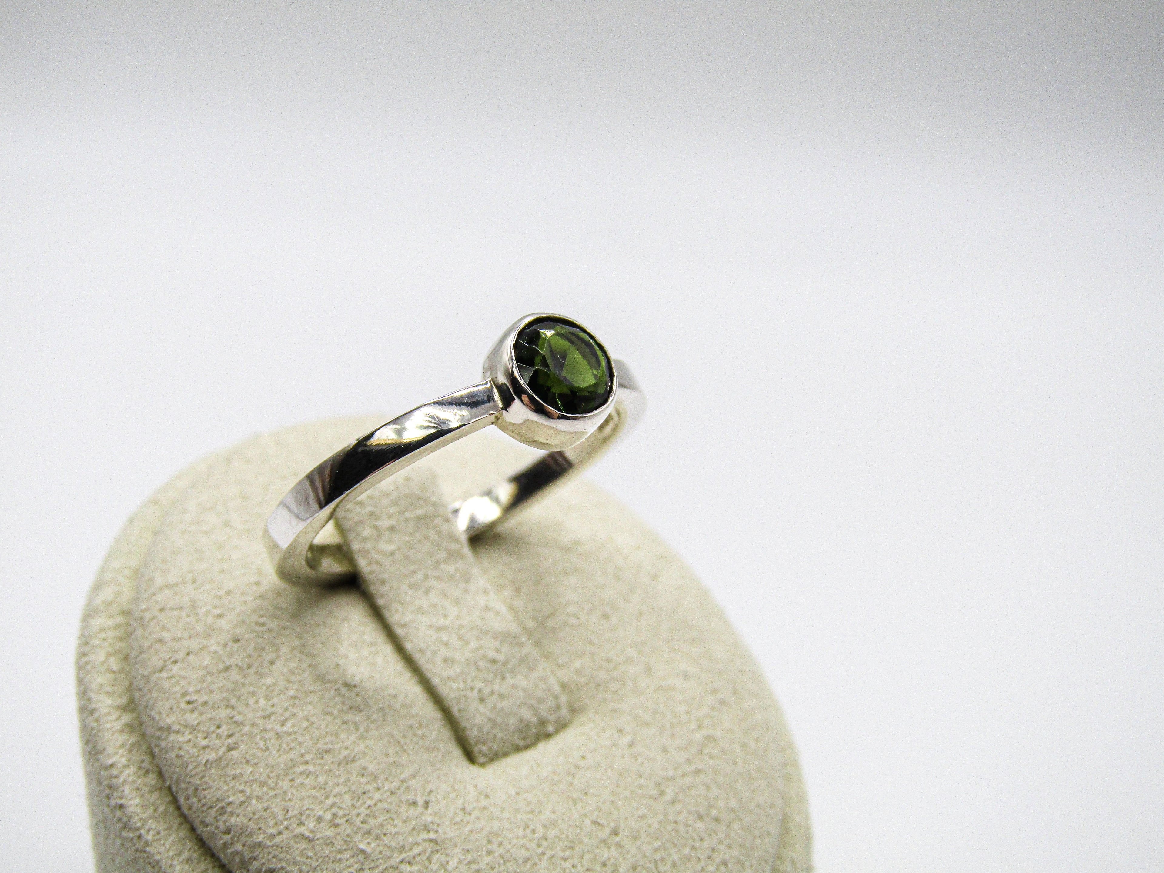 Silver ring with a green gemstone on a white background
