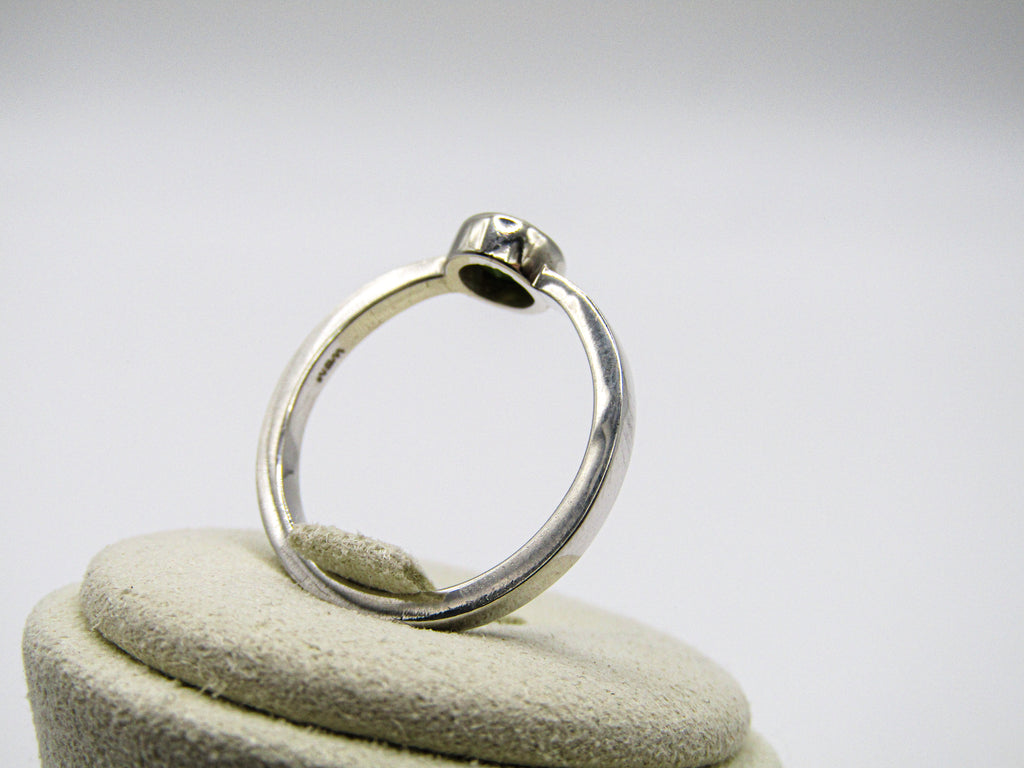 Silver ring on a white cushion with a white background