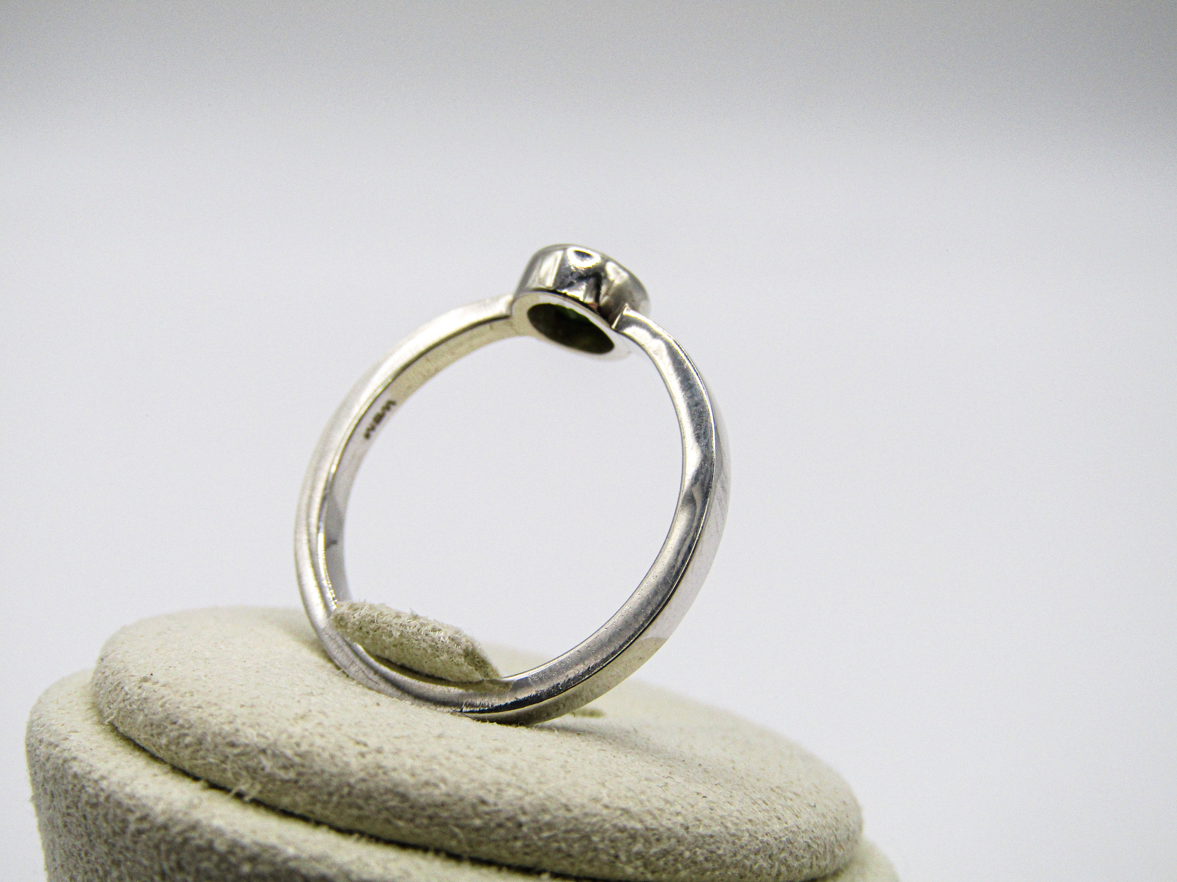 Silver ring on a white cushion with a white background
