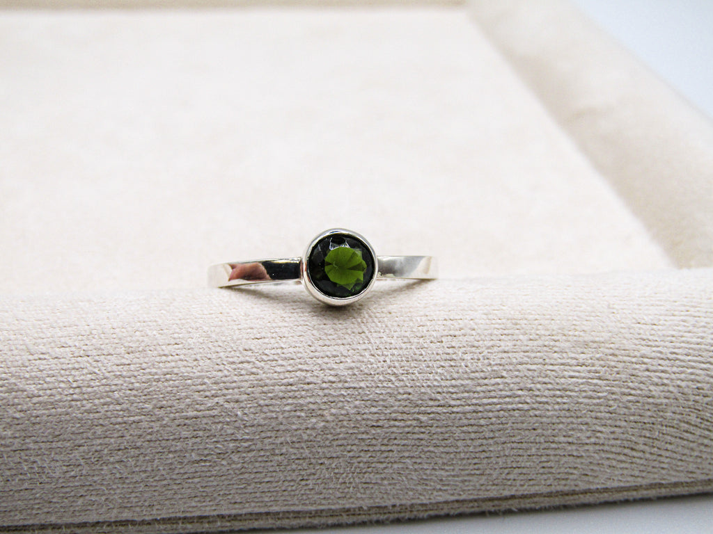 Silver ring with a green gemstone on a textured surface