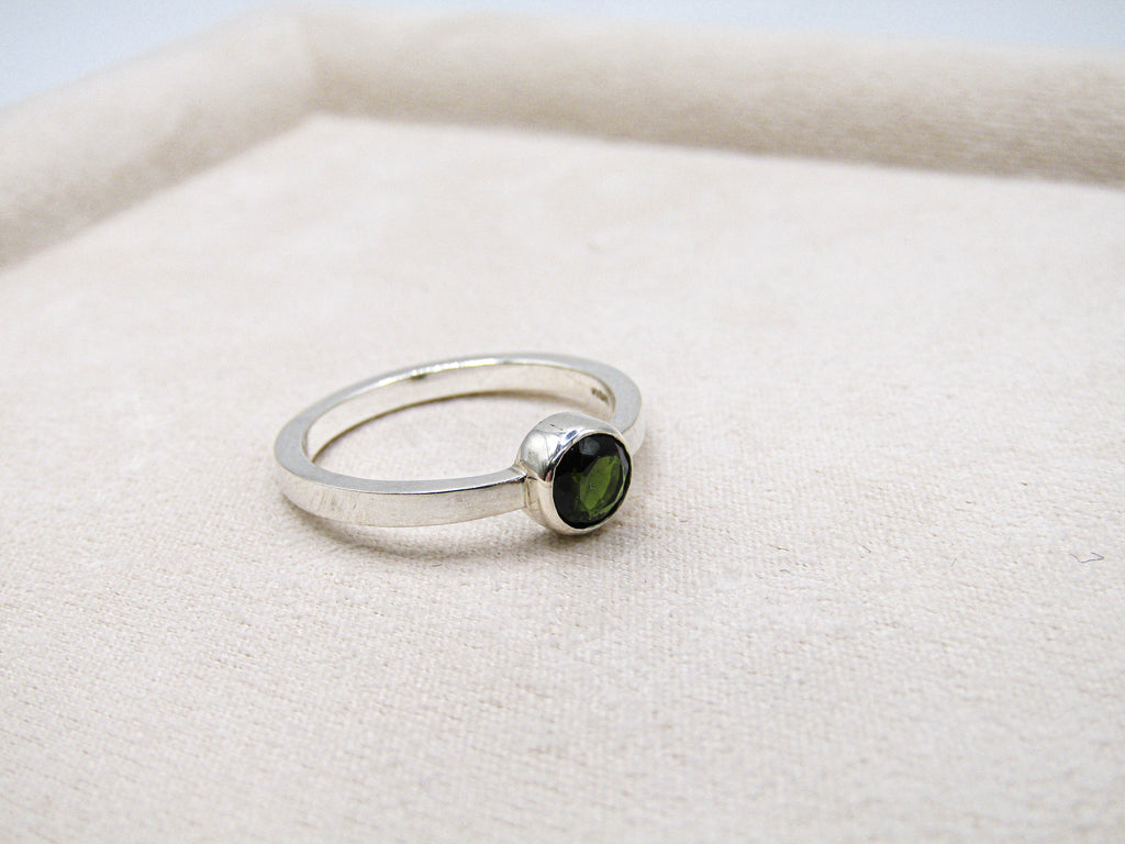 Silver ring with a green gemstone on a white background