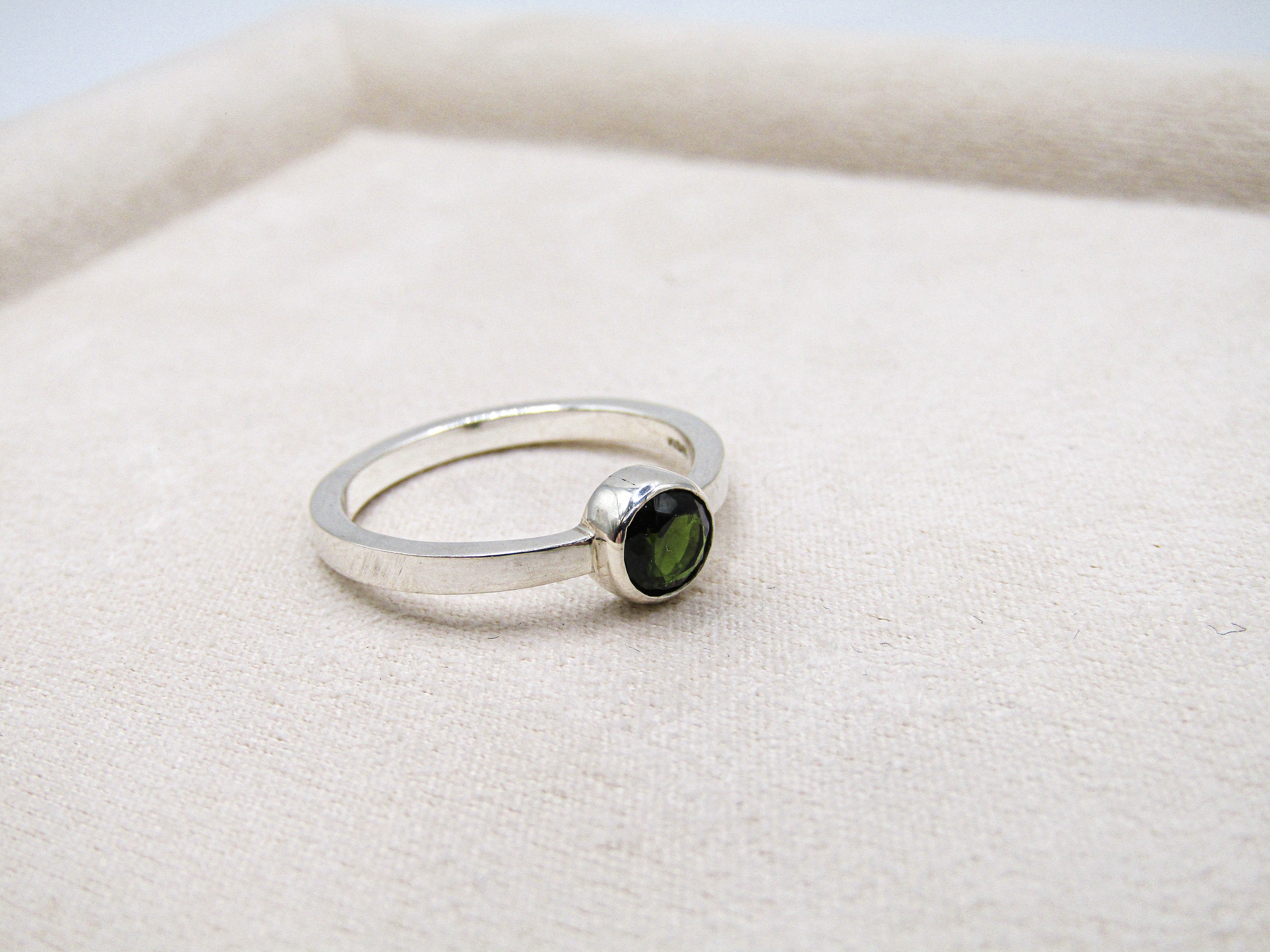 Silver ring with a green gemstone on a white background