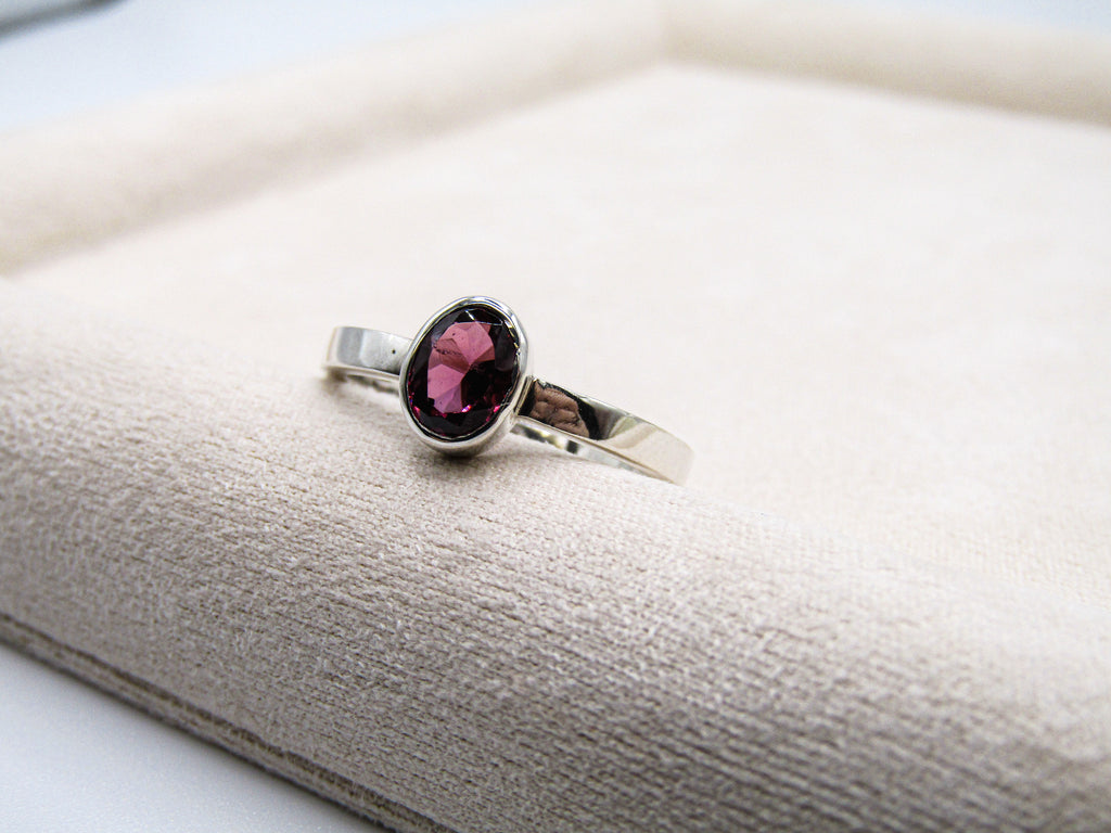 Silver ring with a pink gemstone on a textured surface