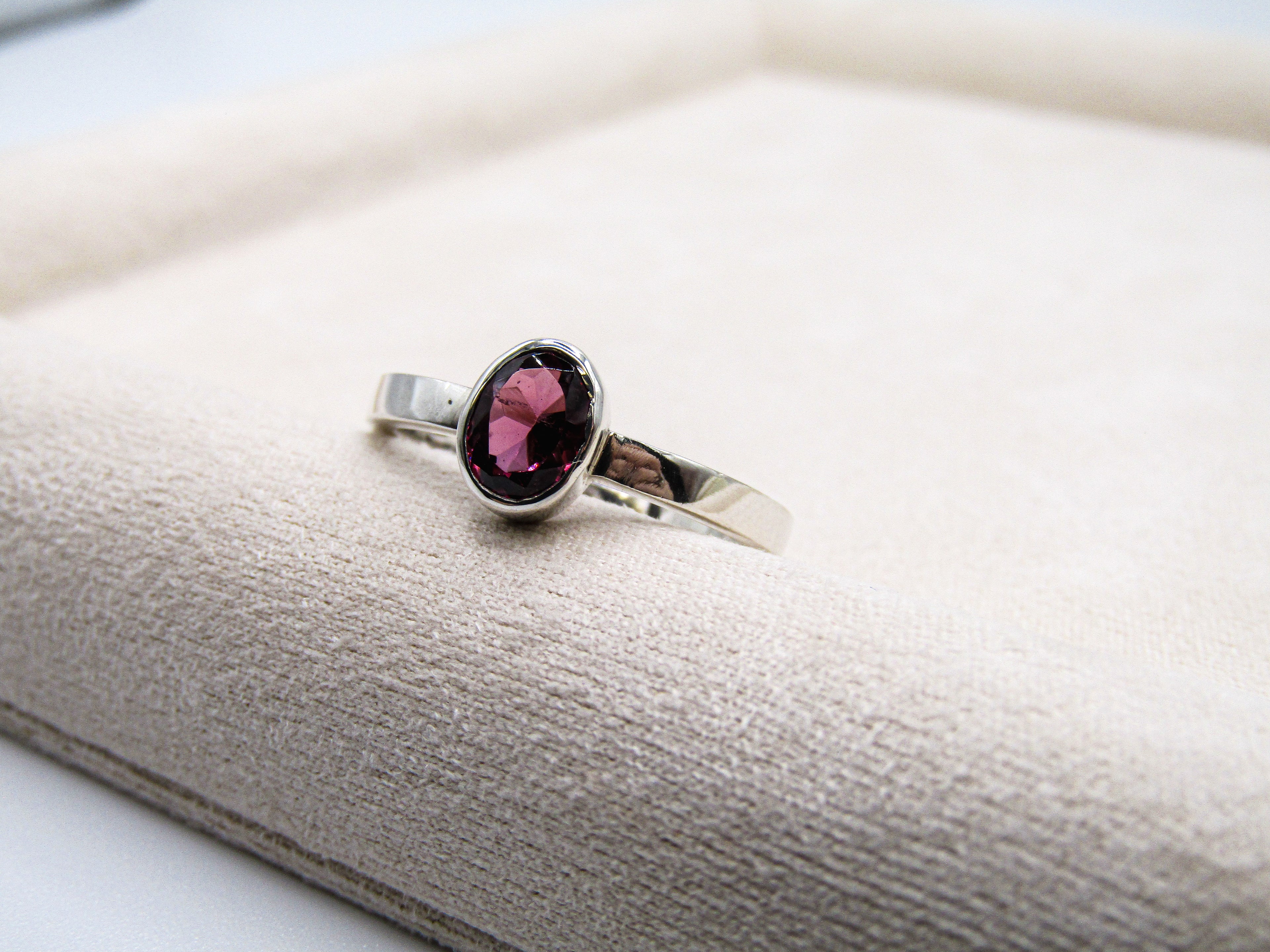 Silver ring with a pink gemstone on a textured surface