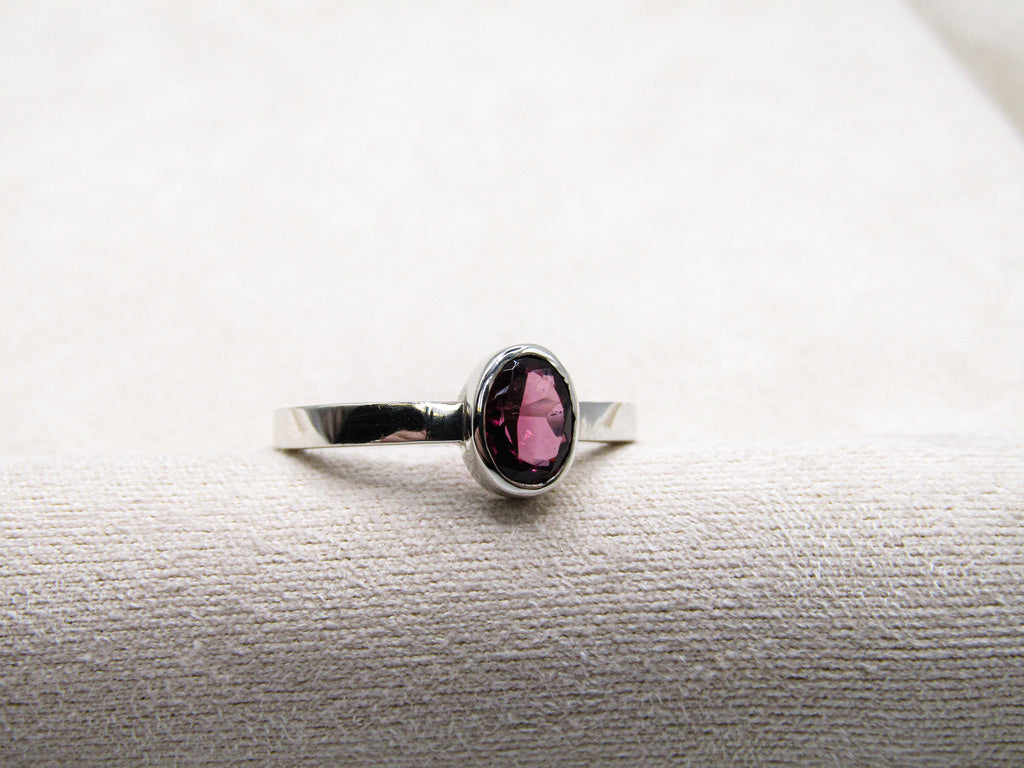 Silver ring with a pink gemstone on a textured white surface