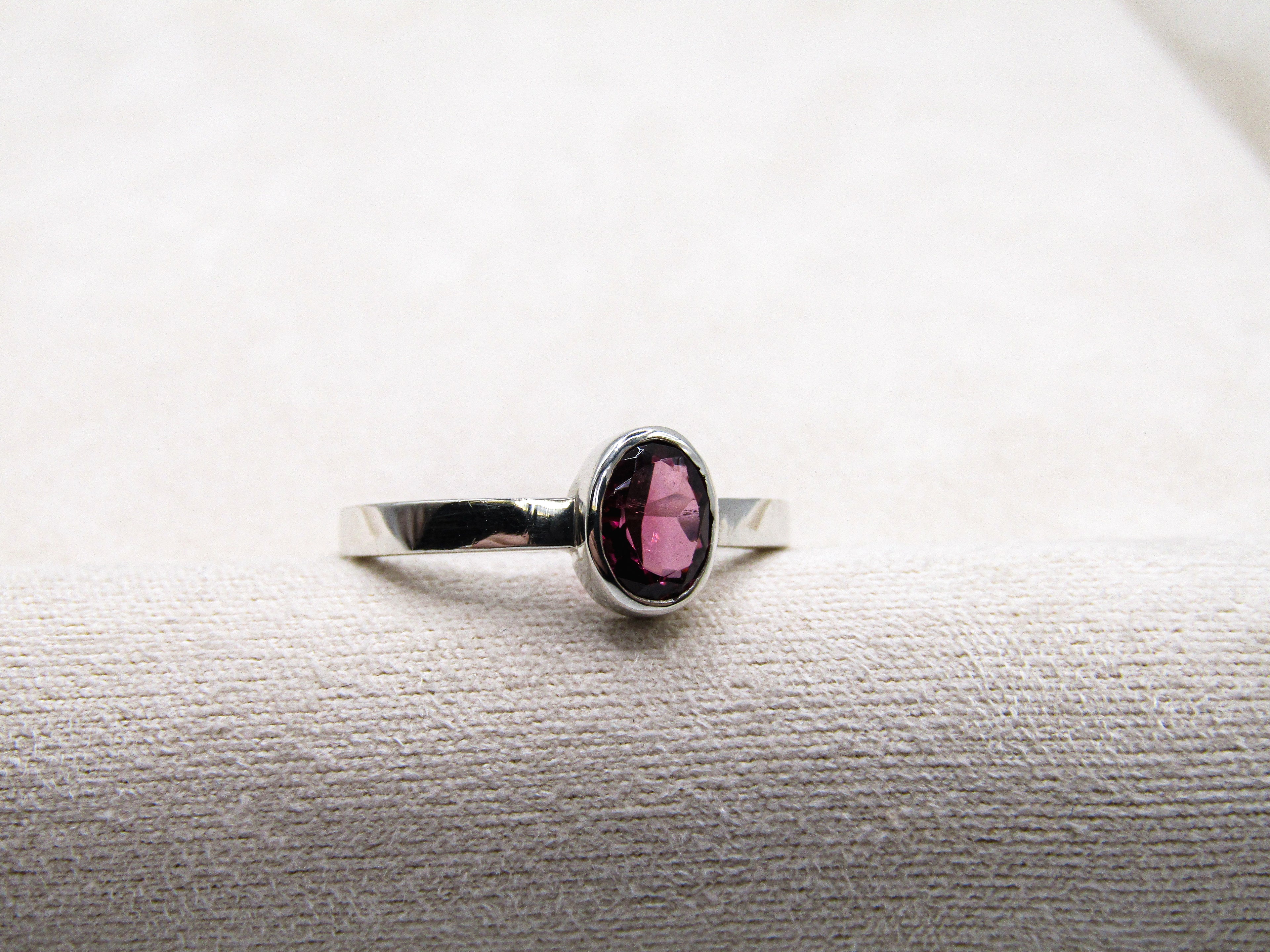 Silver ring with a pink gemstone on a textured white surface