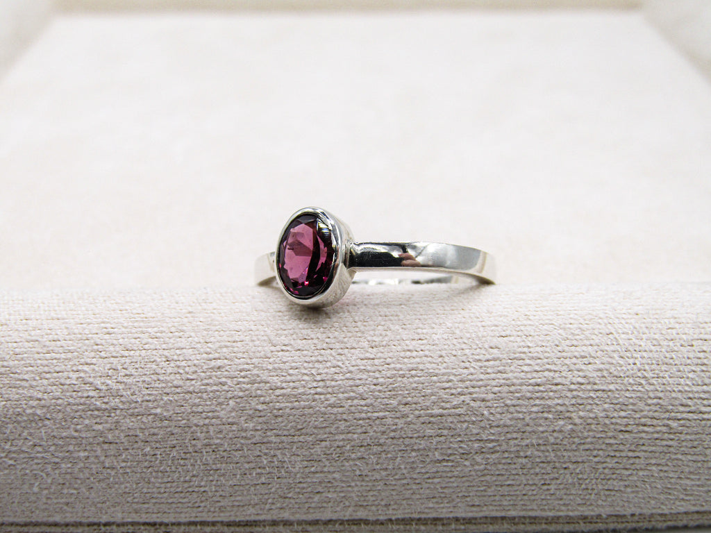 Silver ring with a pink gemstone on a textured surface