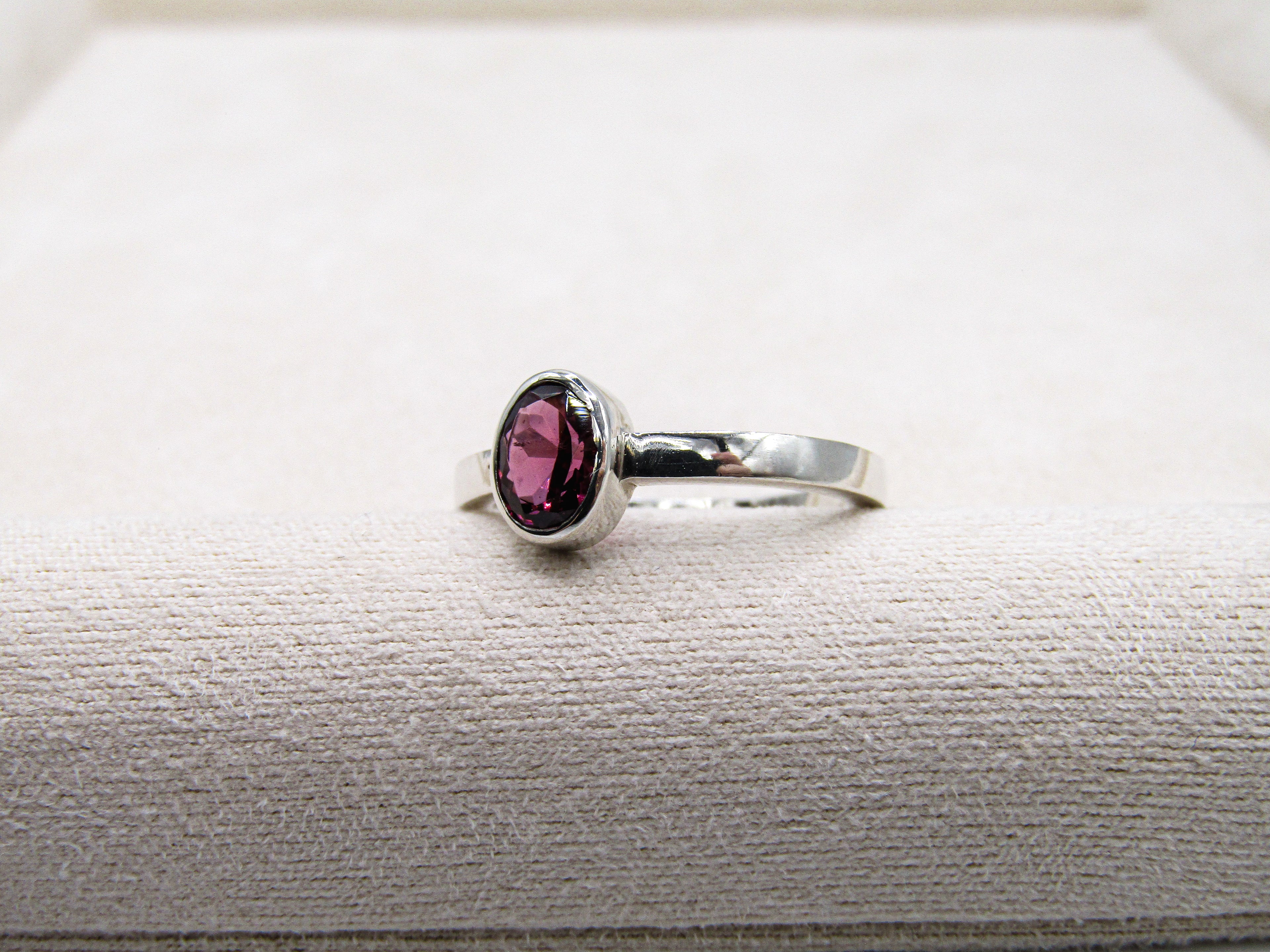 Silver ring with a pink gemstone on a textured surface