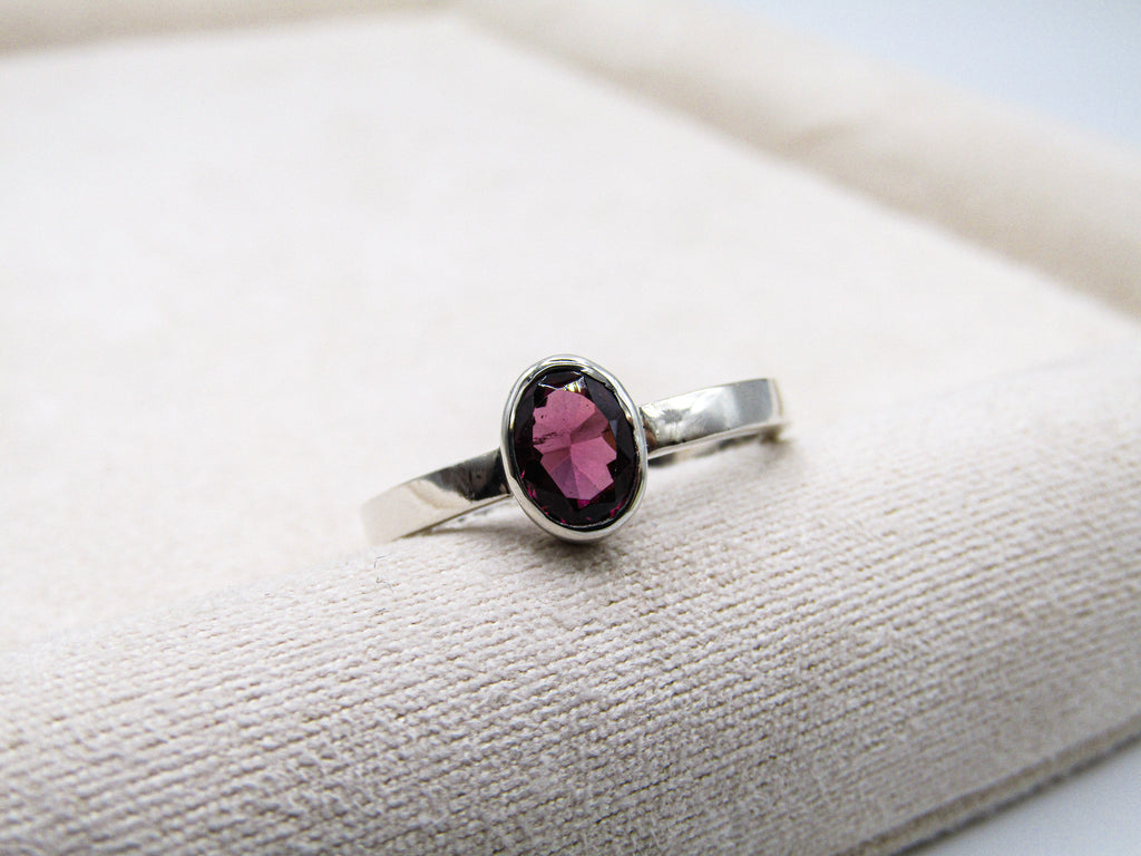 Silver ring with a pink gemstone on a textured surface
