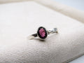 Silver ring with a pink gemstone on a textured surface