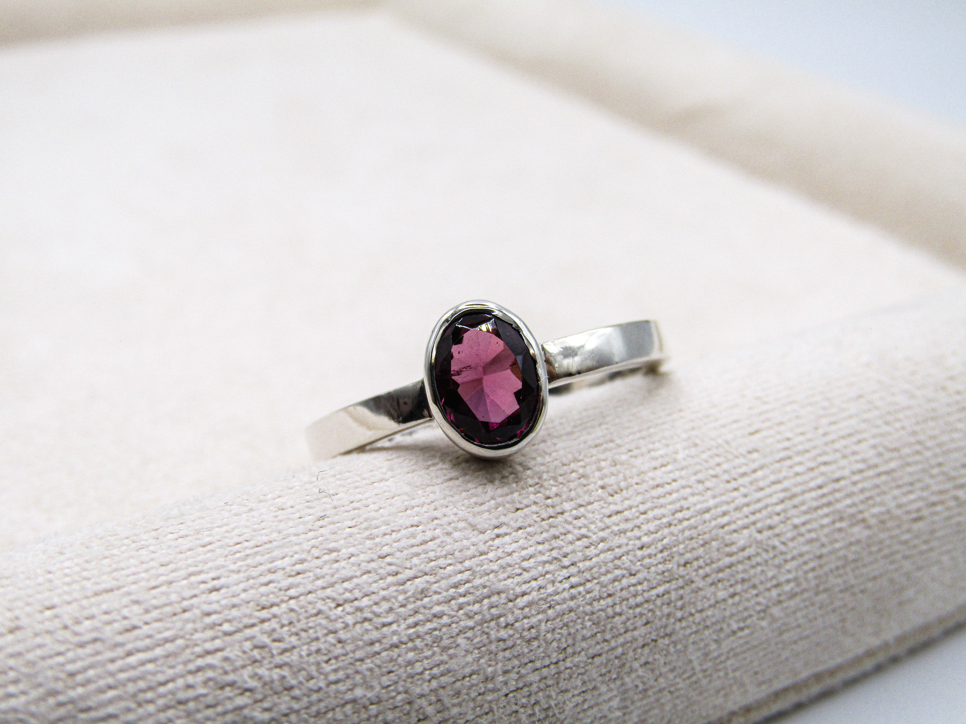 Silver ring with a pink gemstone on a textured surface