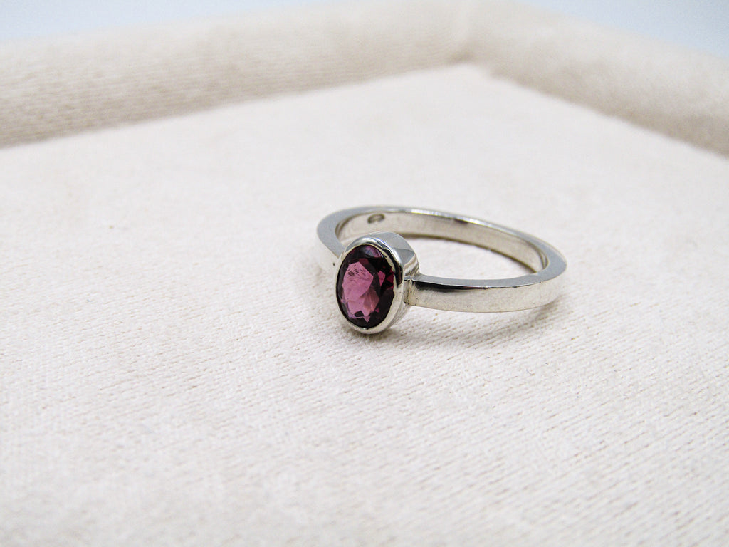 Silver ring with a red gemstone on a white fabric background