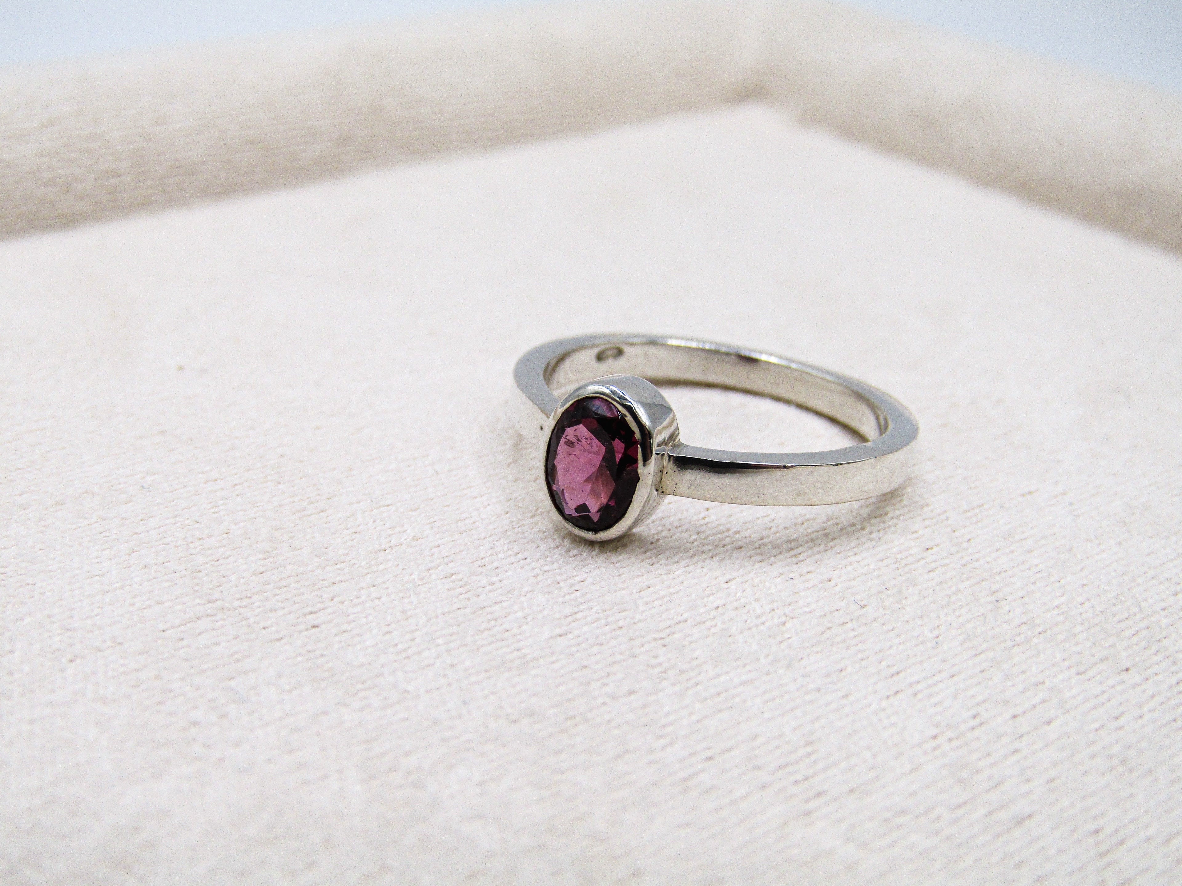 Silver ring with a red gemstone on a white fabric background