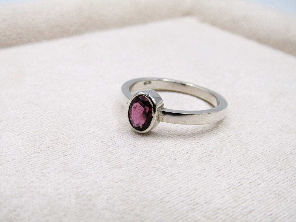 Silver ring with a pink gemstone on a white fabric background