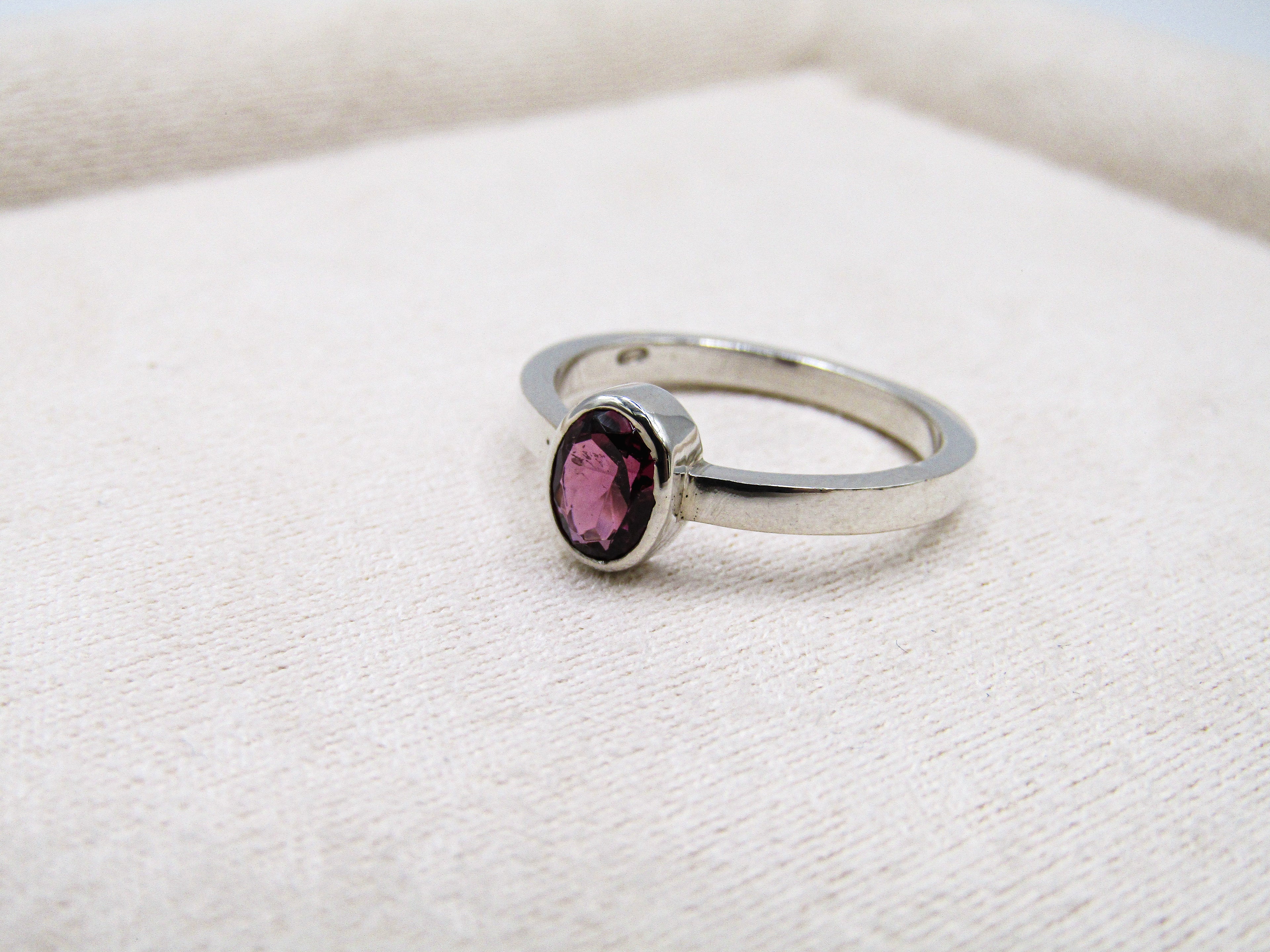 Silver ring with a pink gemstone on a white fabric background