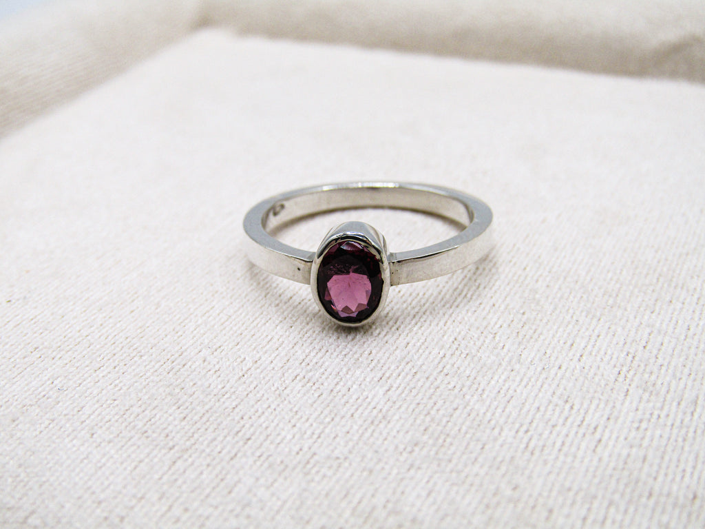 Silver ring with a pink gemstone on a white fabric background