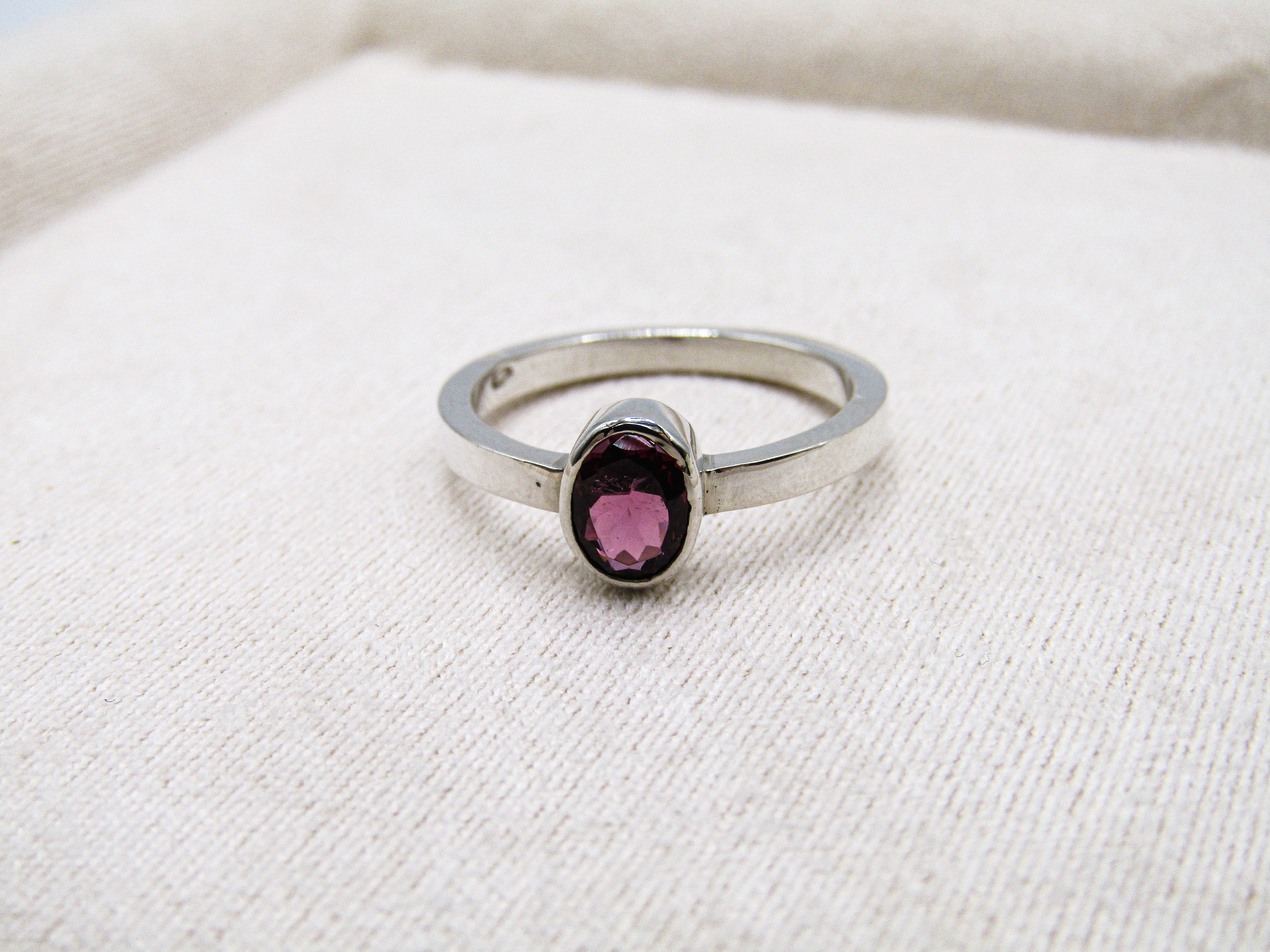 Silver ring with a pink gemstone on a white fabric background