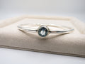 Silver bracelet with a blue gemstone on a beige cushion
