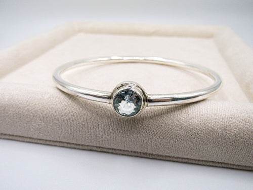 Silver bracelet with a gemstone on a beige cushion