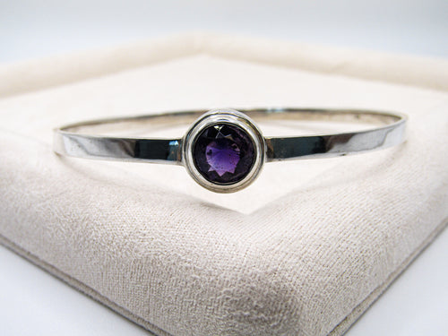 Silver bracelet with a purple gemstone on a textured surface