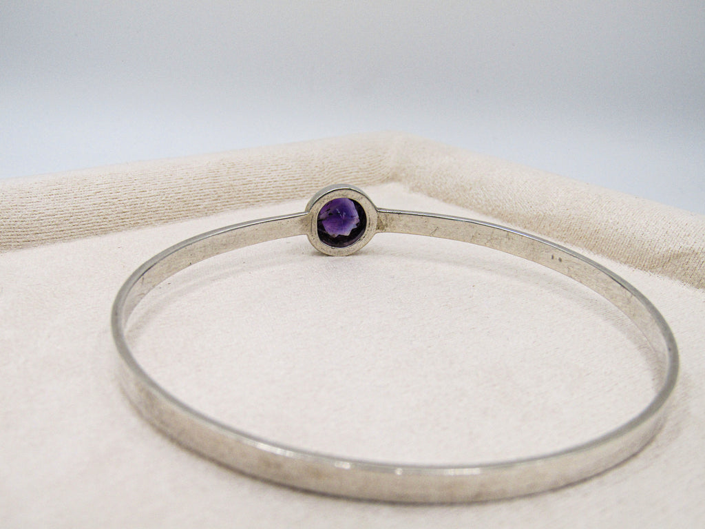 Silver bracelet with a purple gemstone on a white background