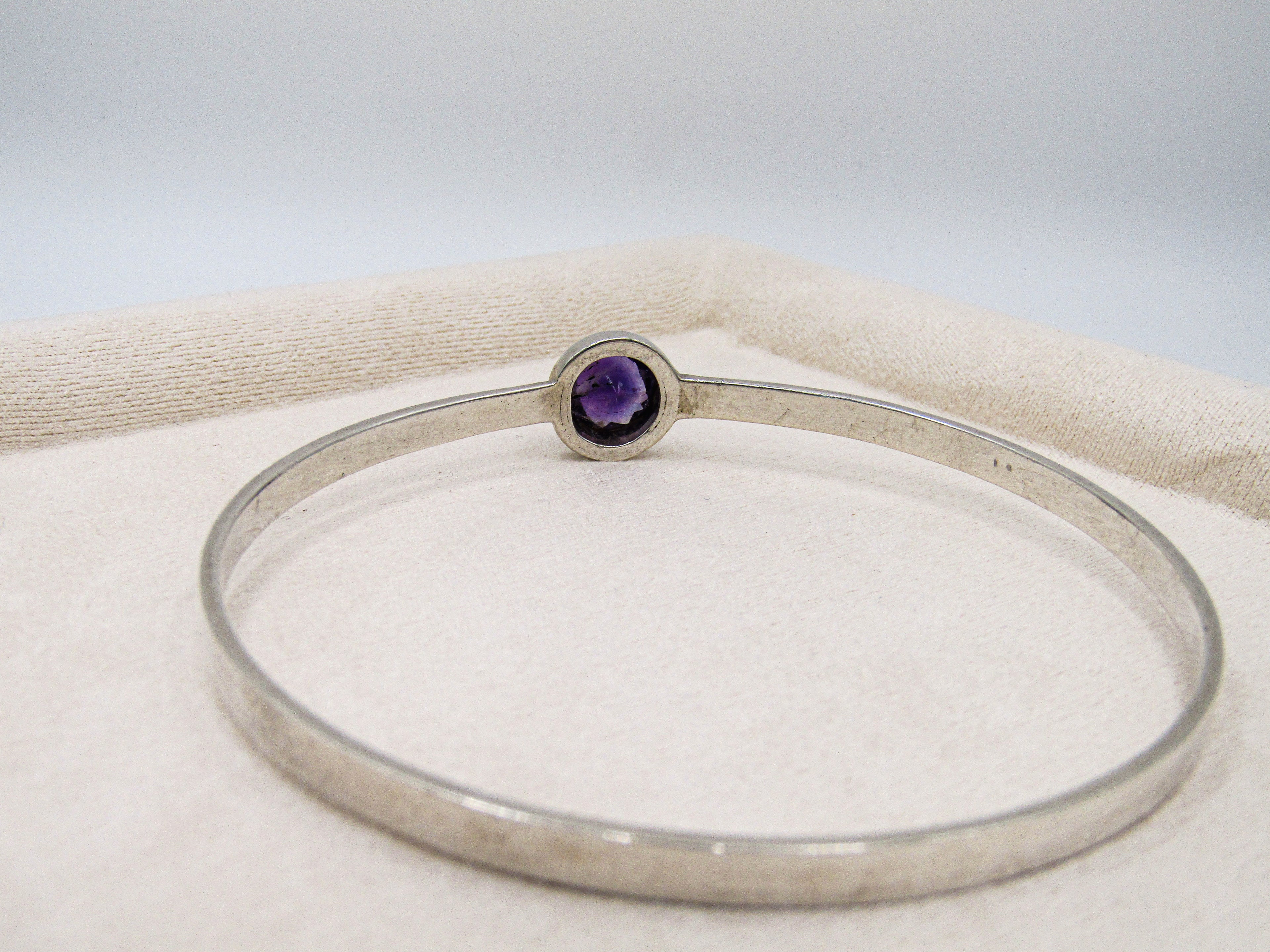 Silver bracelet with a purple gemstone on a white background