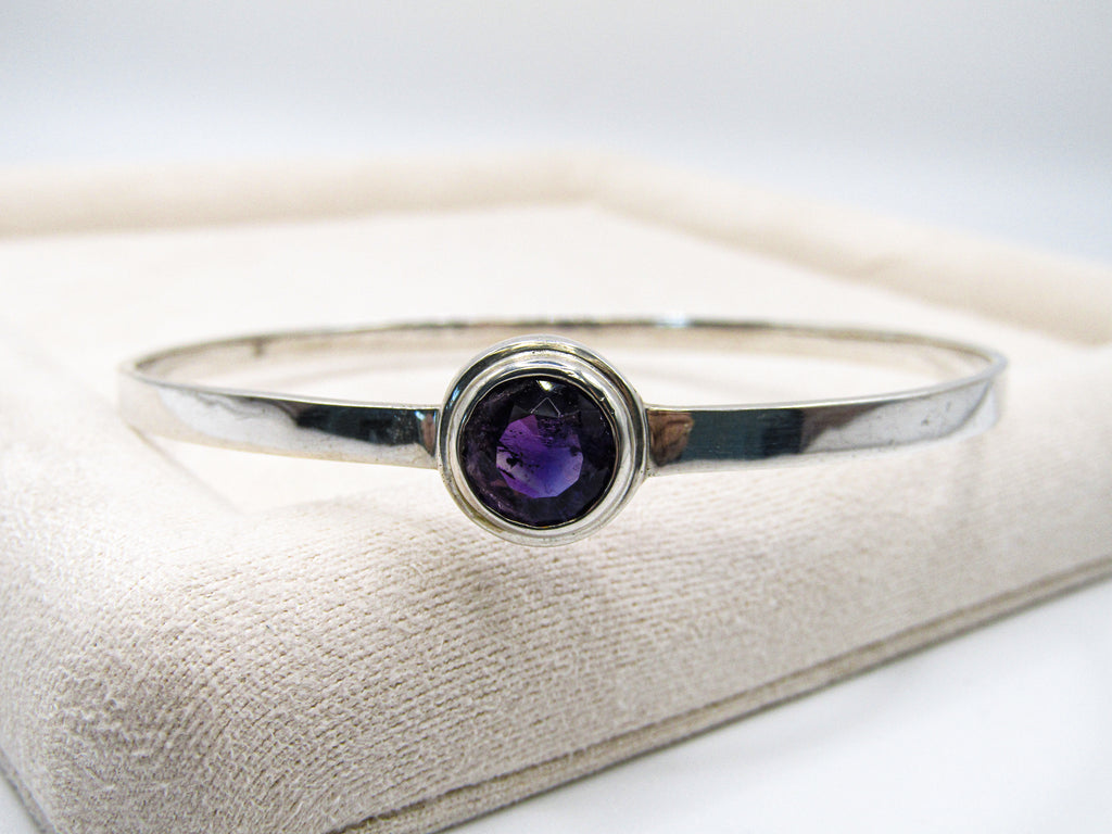 Silver ring with a purple gemstone on a white background