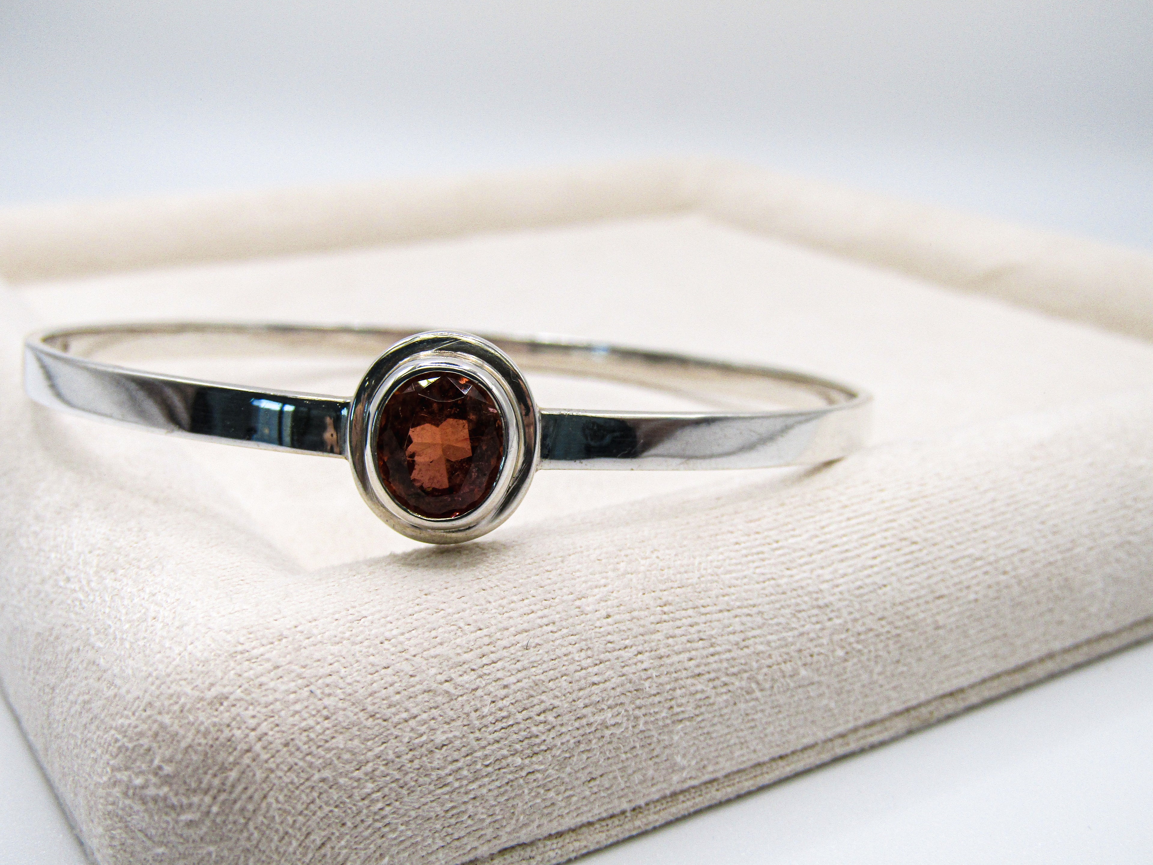 Silver bracelet with a brown gemstone on a white surface