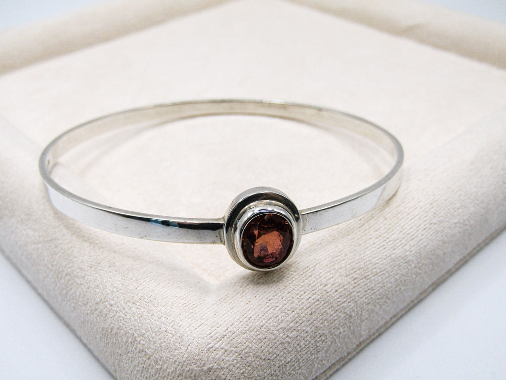 Silver bracelet with a round amber stone on a white surface